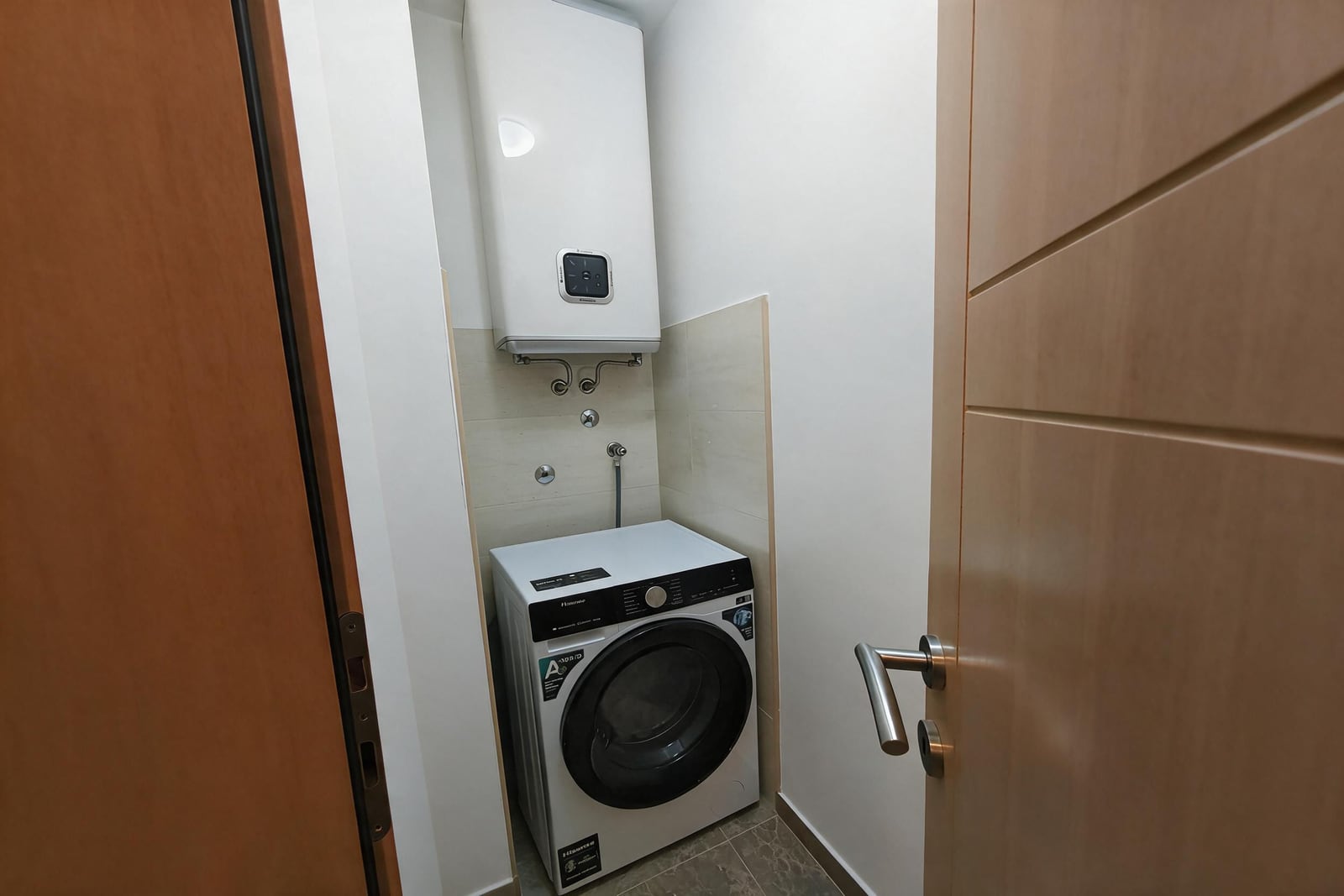 Laundry area in an apartment in Bečići, Montenegro: washing machine and water heater on the wall