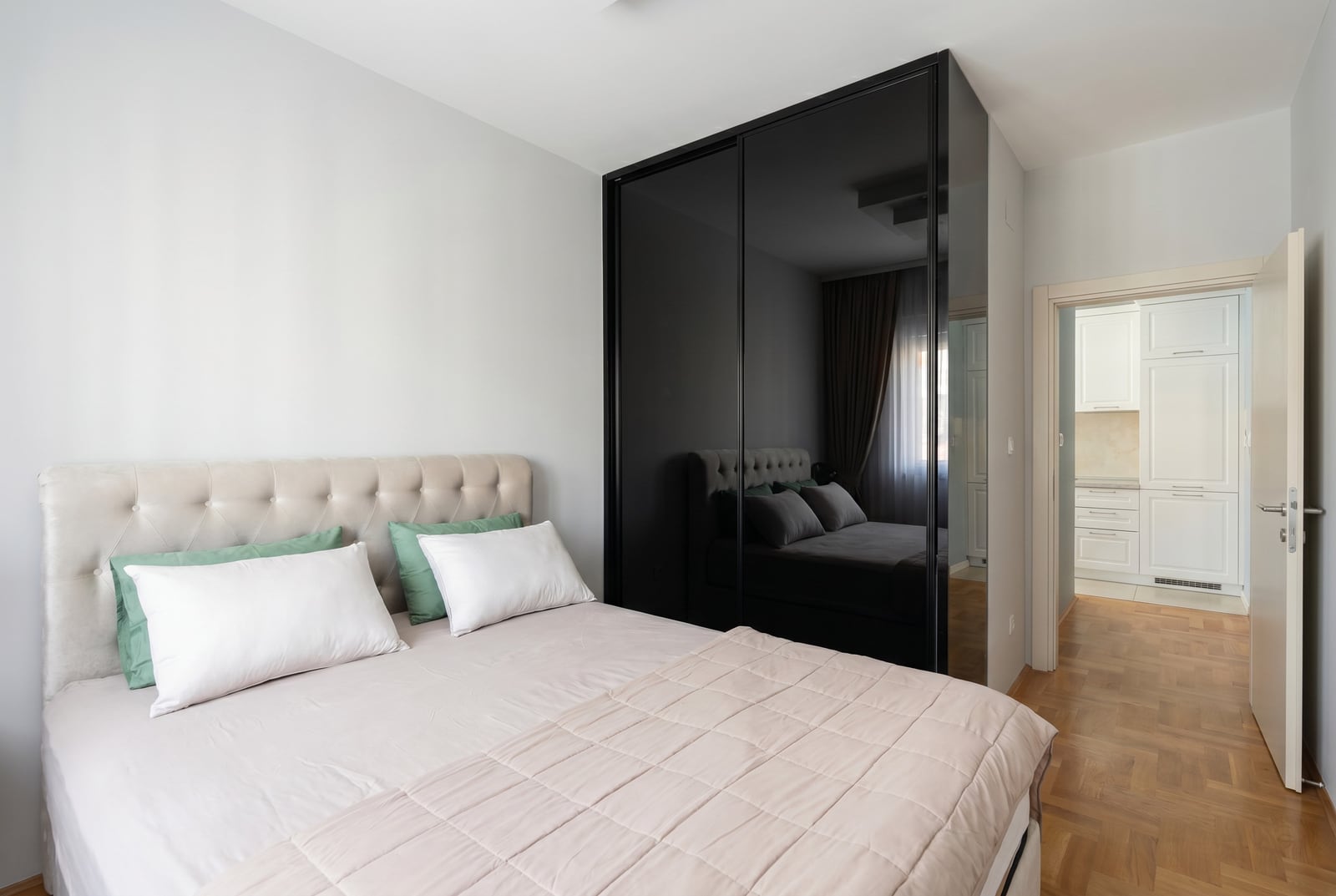 Modern bedroom with a double bed and a black mirrored wardrobe in an apartment, Budva, Montenegro.