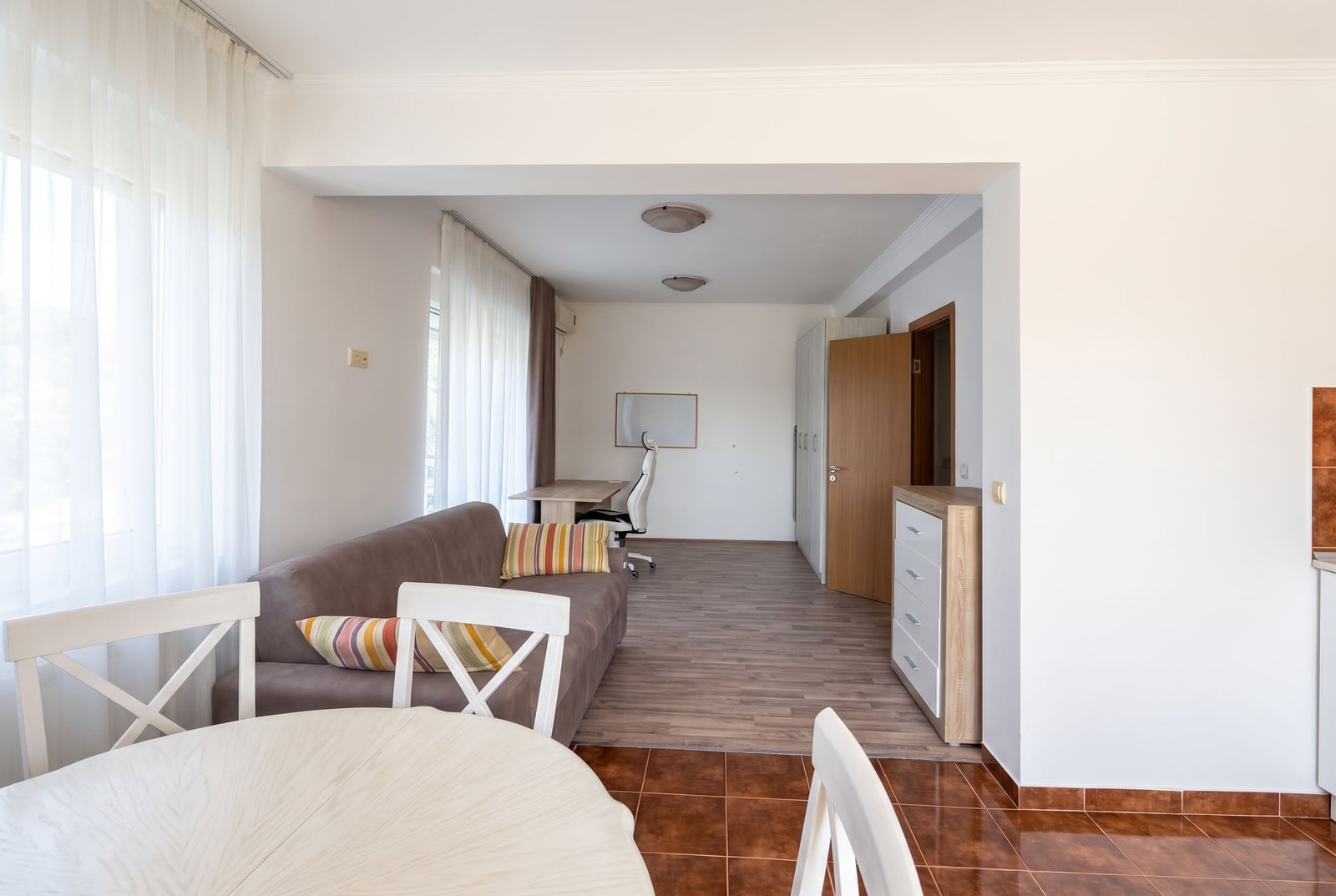 Bright living room with a sofa, work area, and dining table in an apartment in Tivat, Montenegro