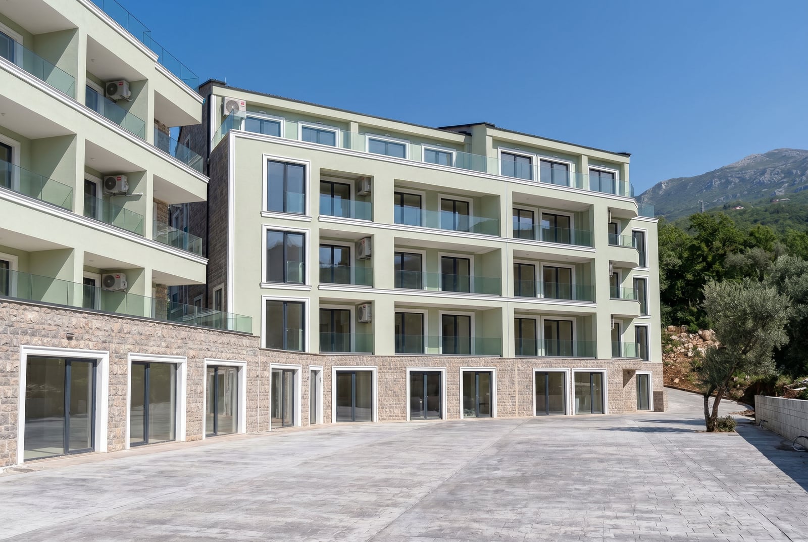 Modern residential complex with terraces in Pržno, Montenegro: stone-clad facade with panoramic windows.