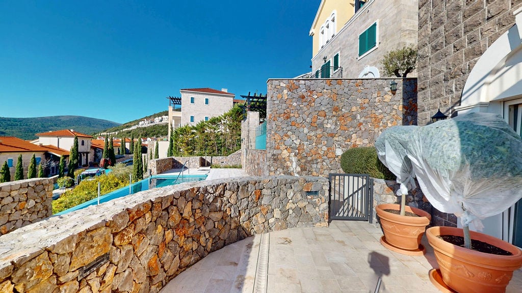 Stone-finished terrace with a swimming pool at the Luštica residential complex, Montenegro, view of Mediterranean villas.