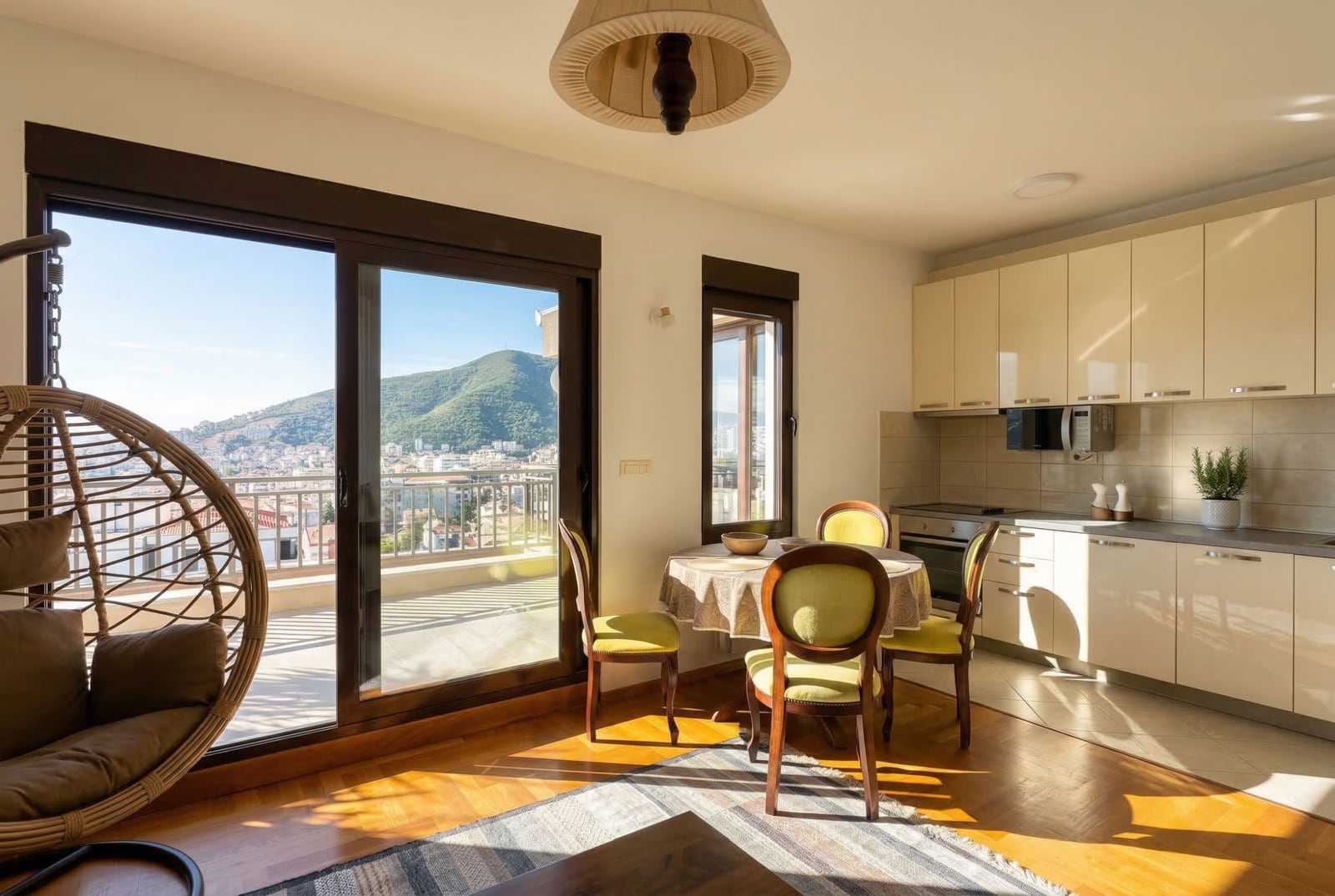Kitchen-living room with access to the terrace and mountain views in an apartment in Budva, Montenegro: bright interior, cocoon chair.
