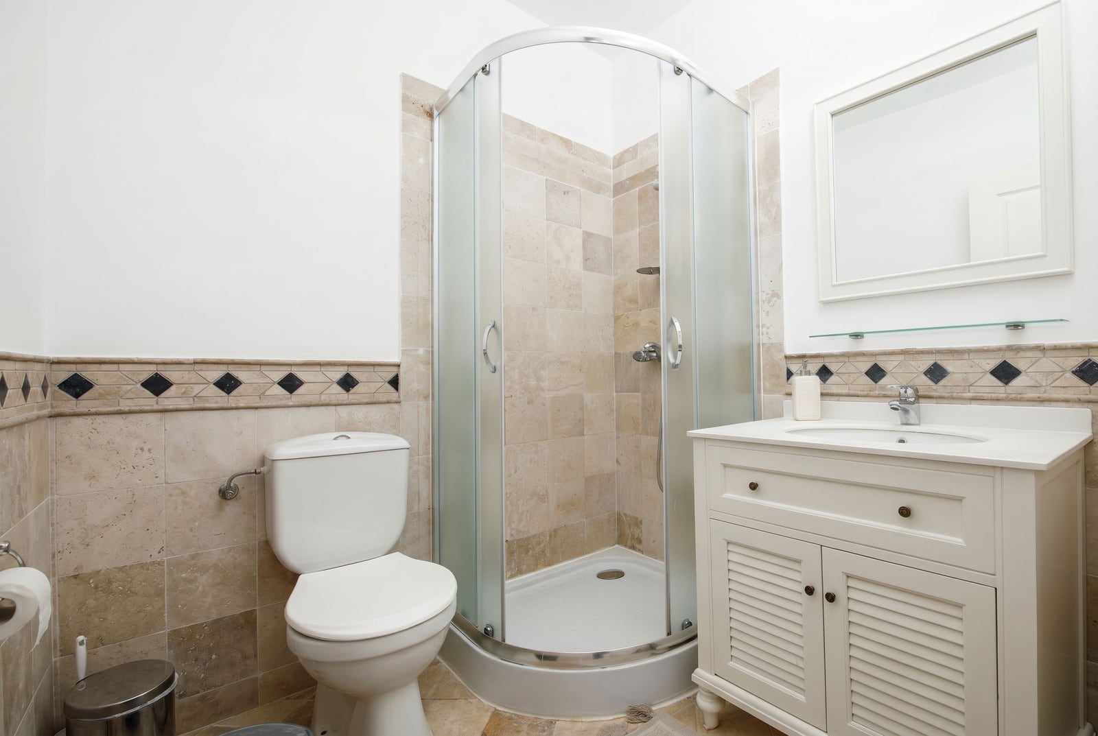 Bathroom in an apartment in Risan, Montenegro: shower cabin, vanity unit with sink, and beige tiles with decorative accents.