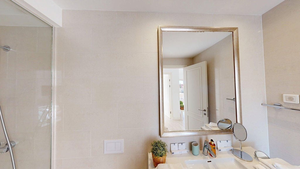 Modern bathroom with a shower cabin and mirror in an apartment, Luštica, Montenegro. Light tile finish.