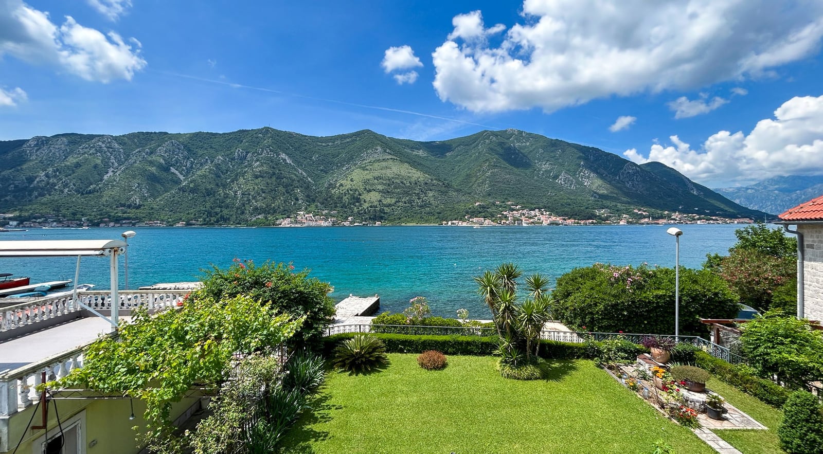 View of Kotor Bay and the mountains from the villa terrace in Dobrota, Montenegro: a well-kept garden, greenery, and direct access to the sea.