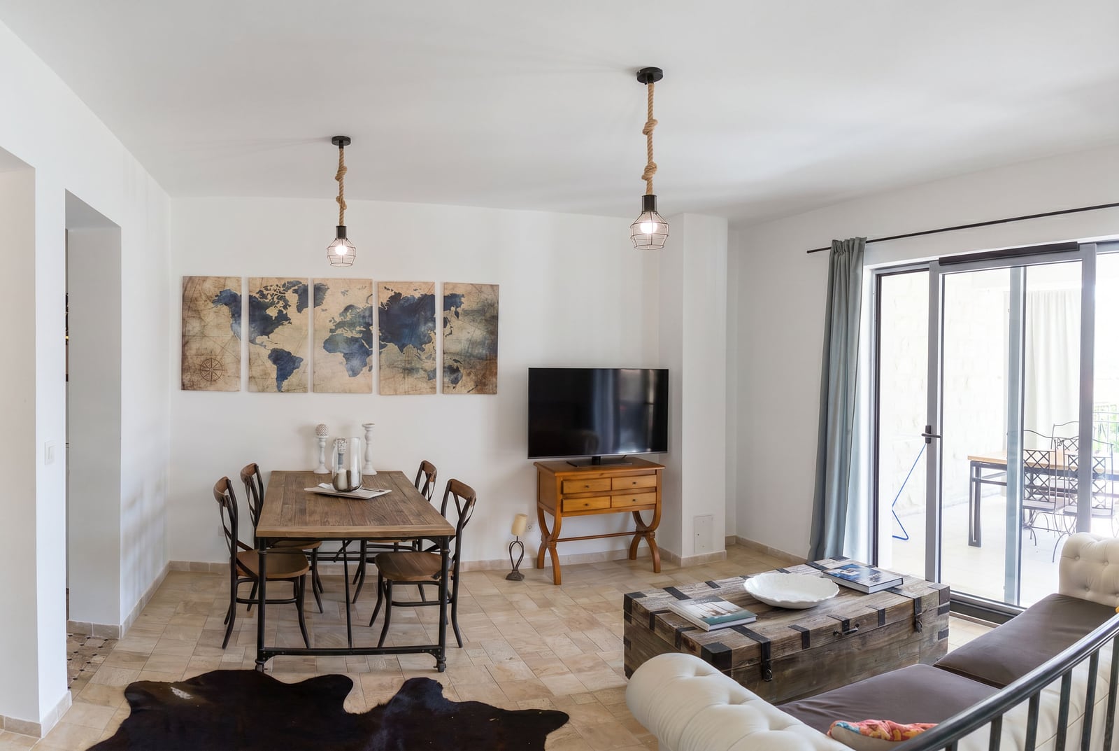 Living room in an apartment in Risan, Montenegro: dining area, vintage furniture, world map decor, and terrace access.