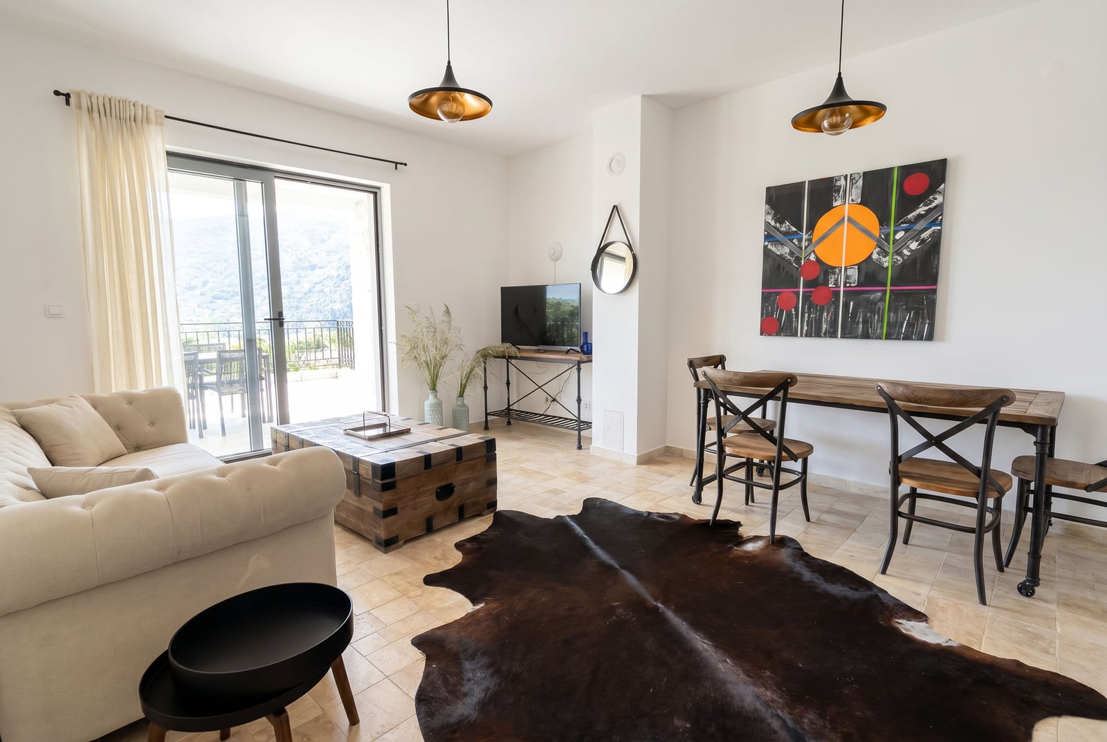 Bright living room in an apartment in Risan, Montenegro: soft sofa, dining area, terrace with mountain views and decor.