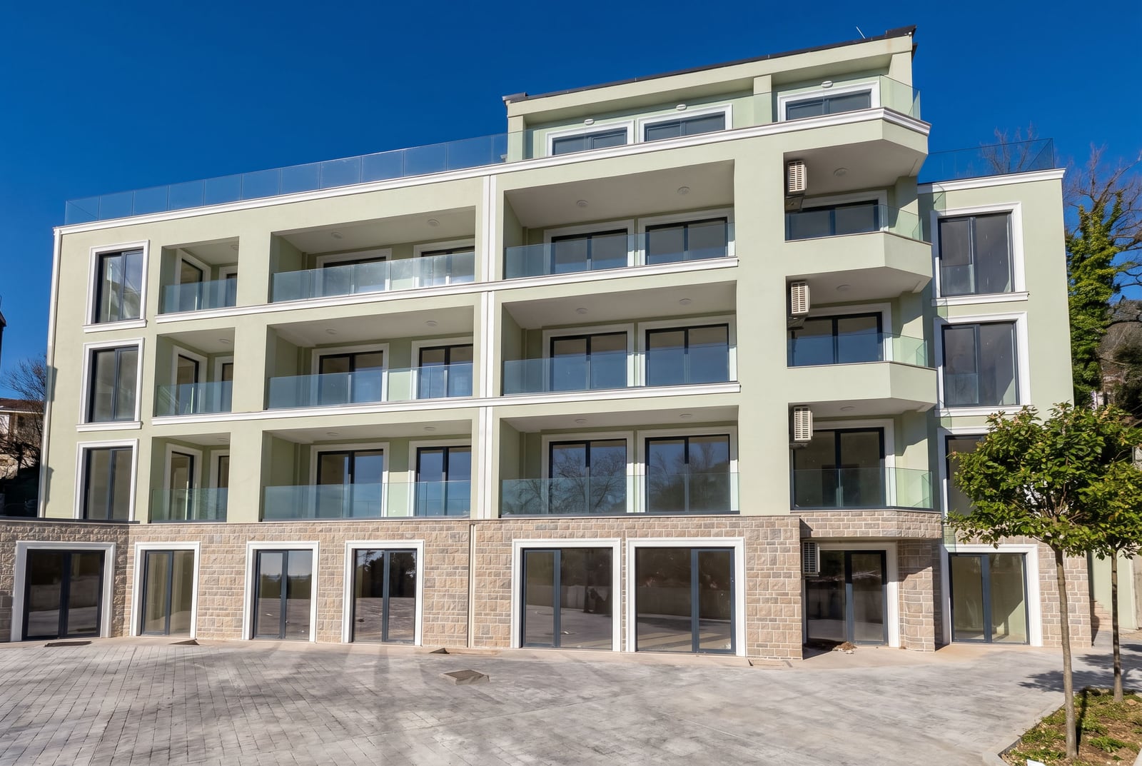 Modern residential complex in Pržno, Montenegro: facade with panoramic windows, terraces, and stone cladding on the base.