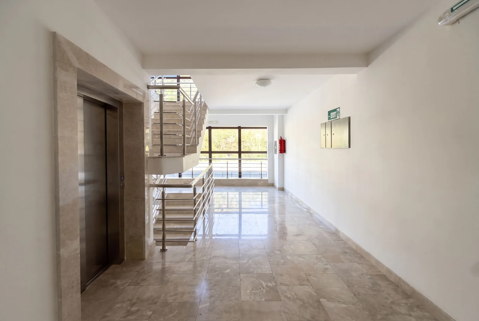 Common hallway featuring an elevator, staircase, mailboxes, fire extinguisher, and marble flooring.