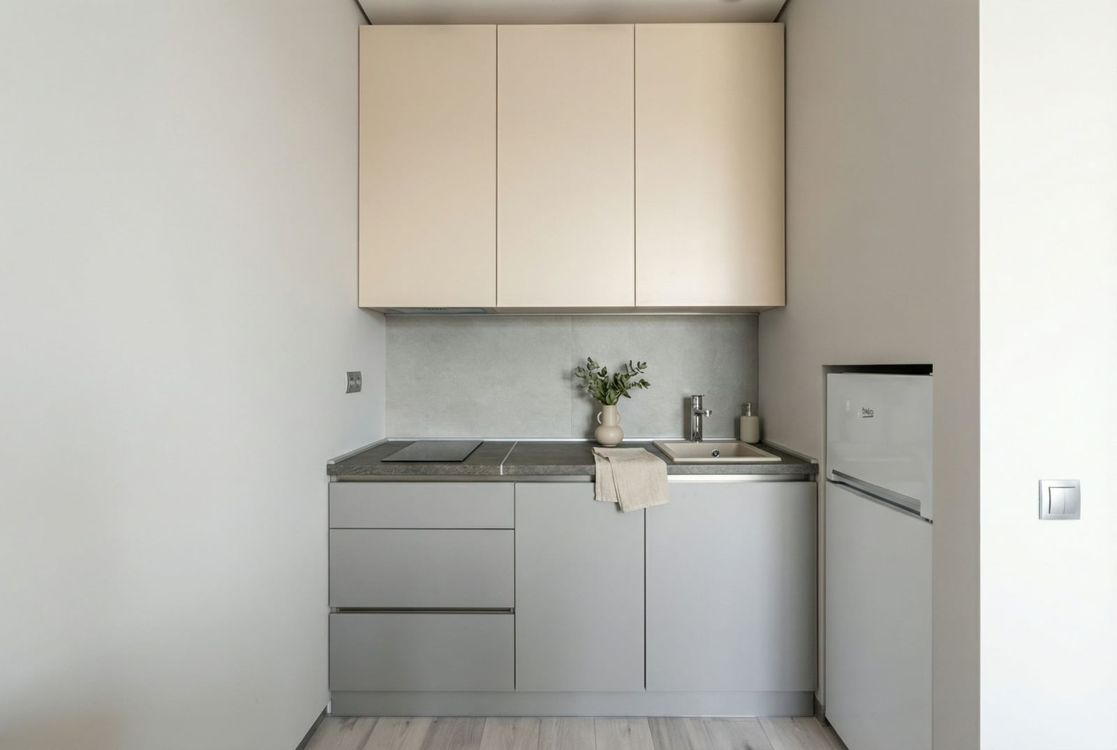 Modern compact kitchen in an apartment in Bečići, Montenegro: light-colored cabinets, built-in appliances, and a stone countertop.