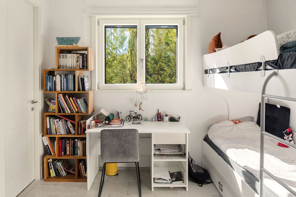 Children's bedroom with a bunk bed and a desk in a townhouse, Luštica, Montenegro. View of greenery from the window.