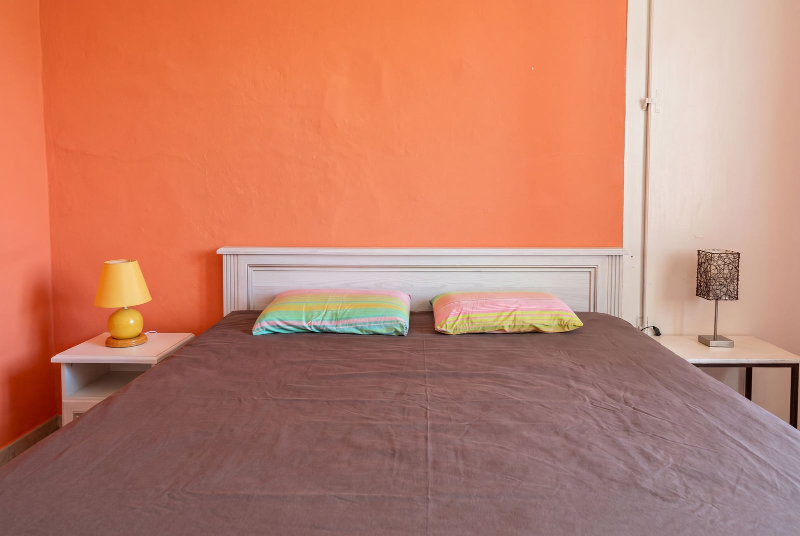 Bedroom in a house in Dobrota, Montenegro: double bed with a brown bedspread, bedside tables, and orange walls.
