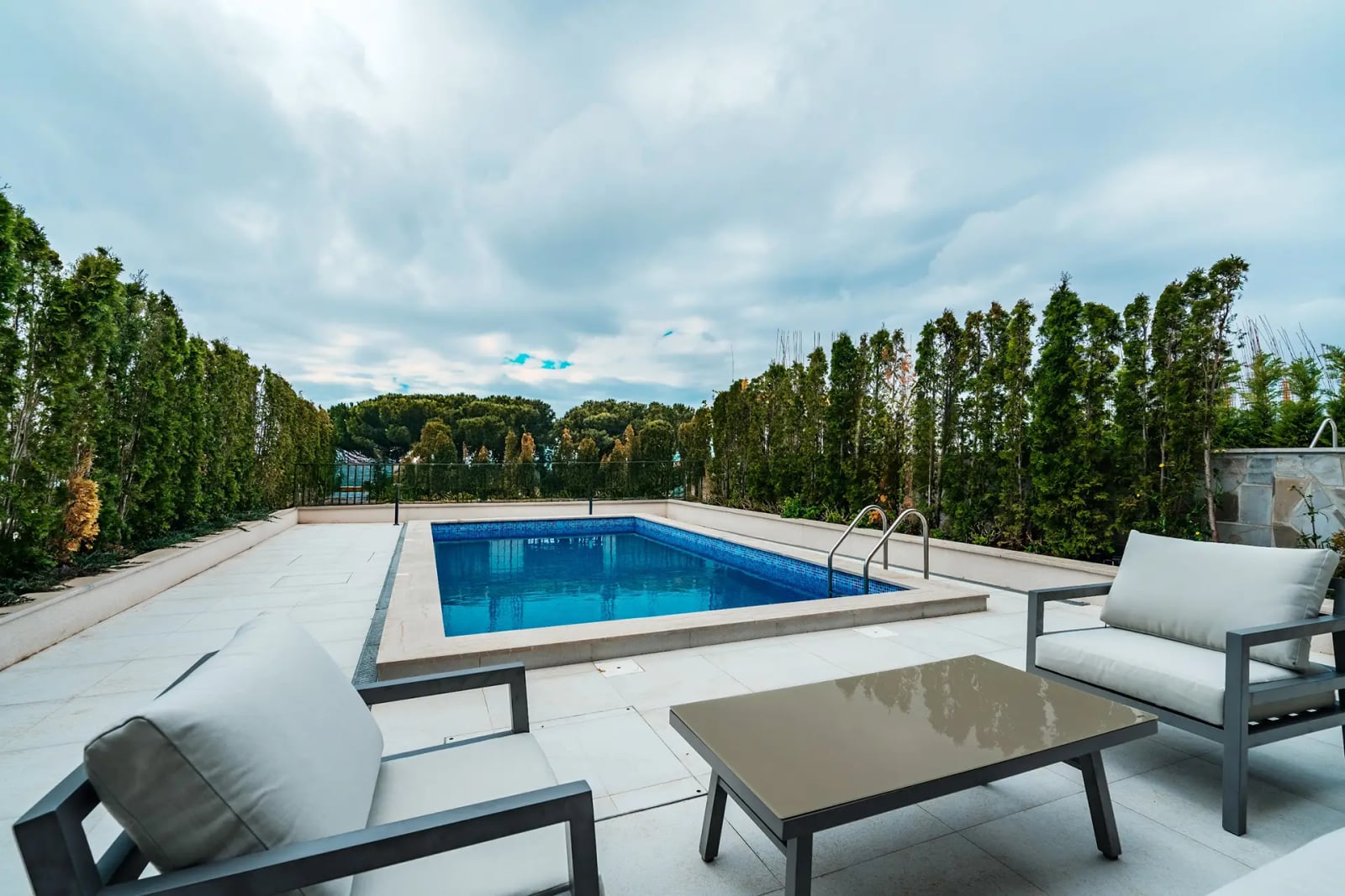 Open terrace with a swimming pool and lounge area at a villa in Reževići, Montenegro: modern furniture and landscape design.
