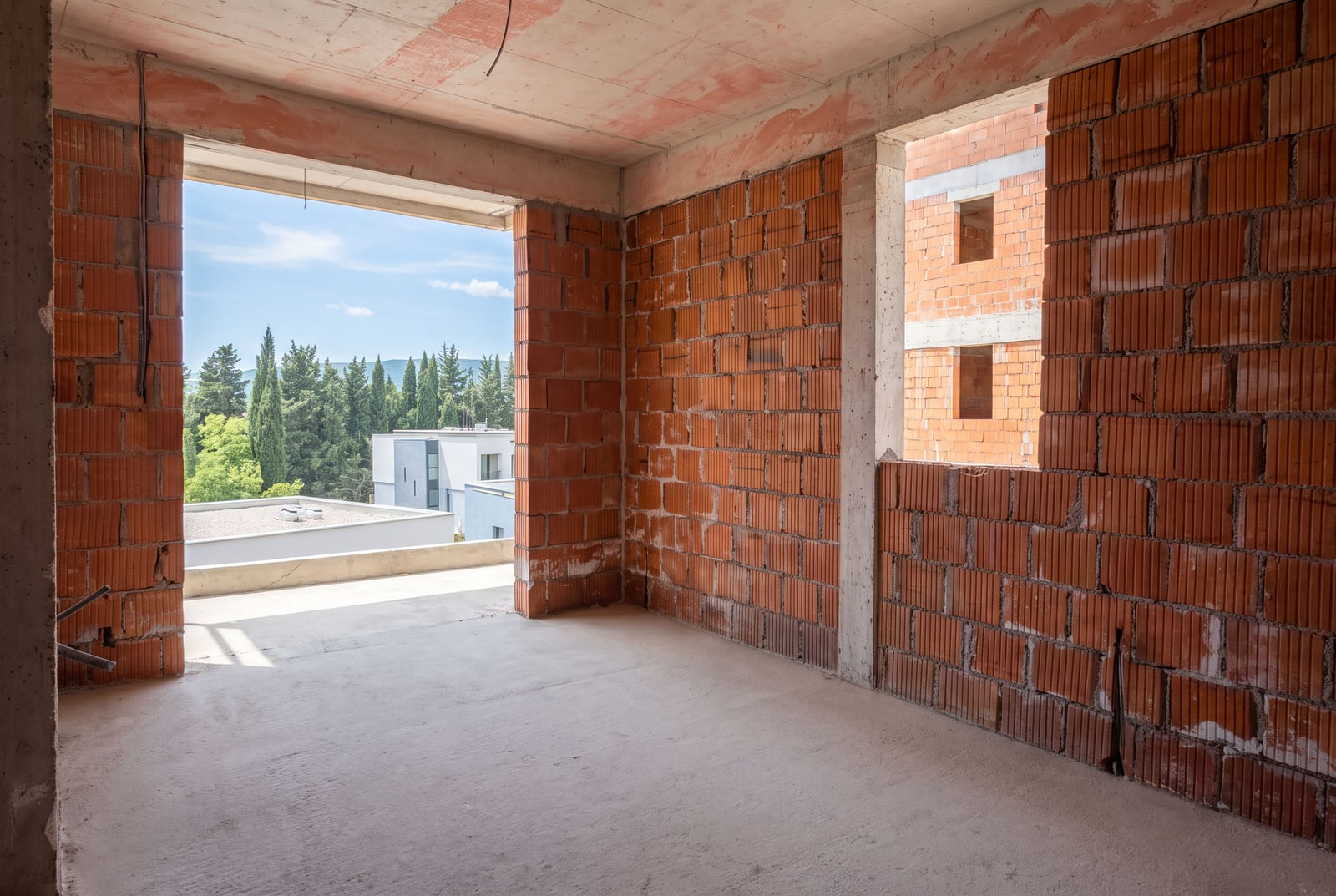 Apartment in a new development in Tivat without finishing, brick walls and a view from the window onto greenery in Montenegro.