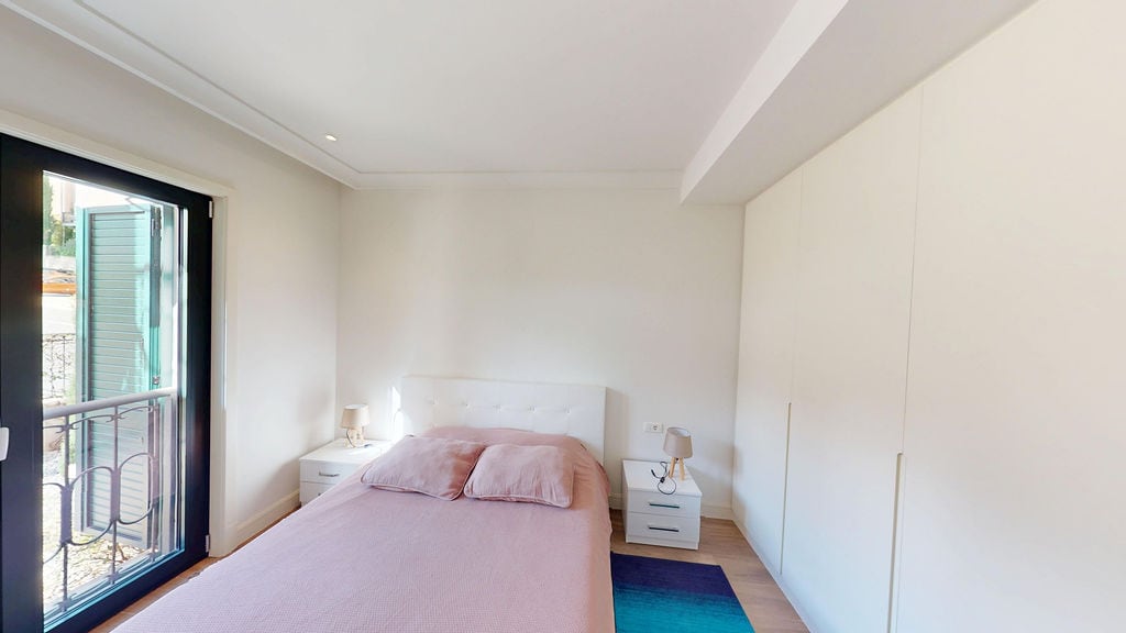 Bright bedroom with a double bed and built-in wardrobe in the Lustica Bay apartment, Montenegro.