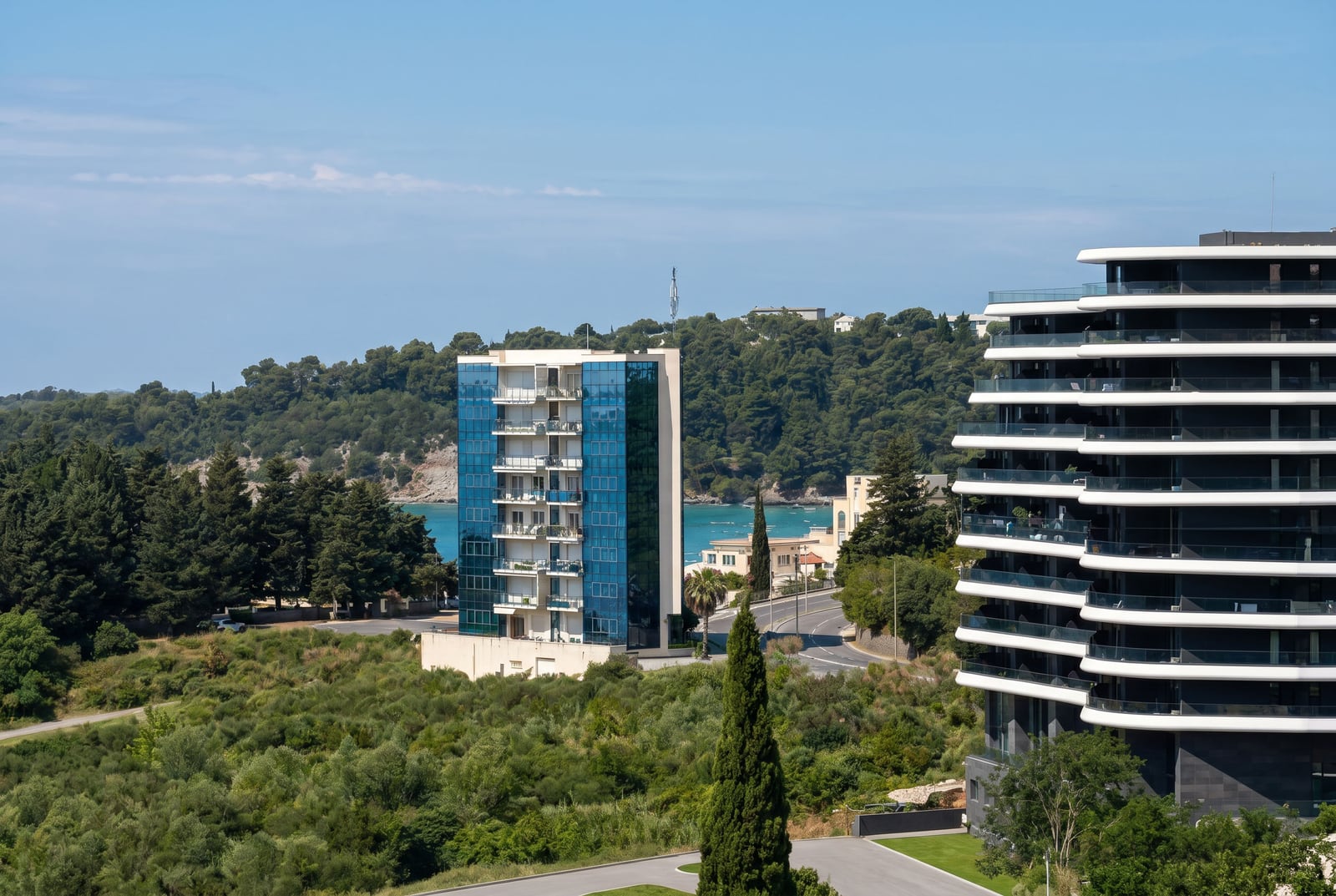 Modern residential complexes in Becici, Montenegro: a view of high-rise buildings, the sea, and the resort's green landscape.