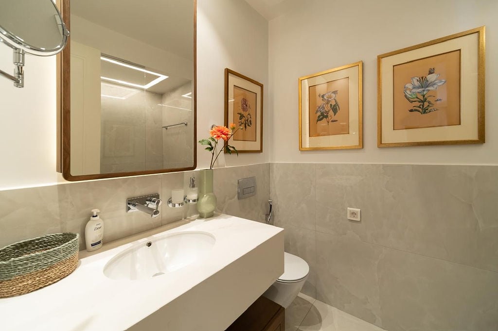Modern bathroom in an apartment in Luštica, Montenegro: light finishes, a wall-mounted sink, and framed decor.