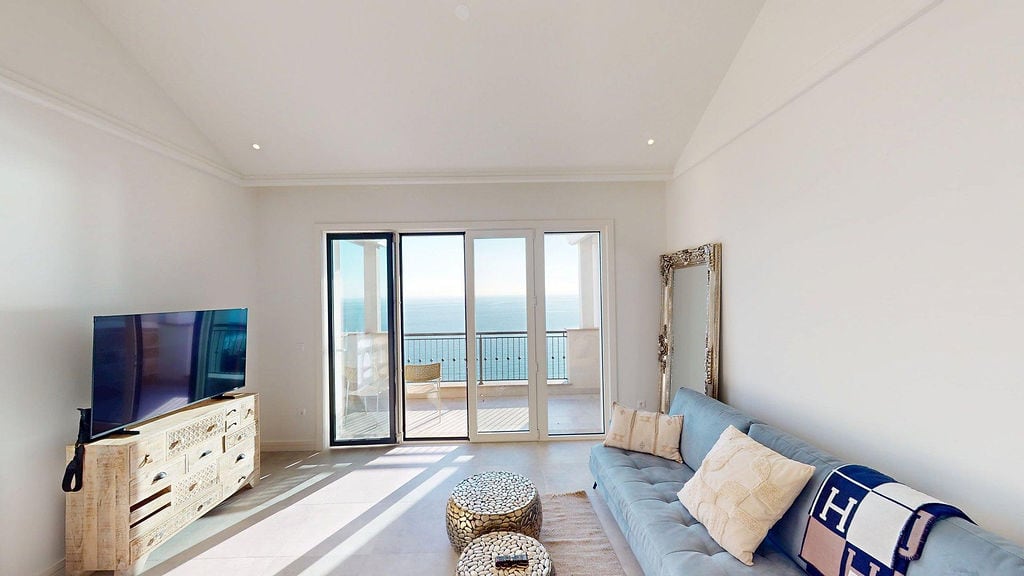 Bright living room with sea view in Luštica Bay apartments, Montenegro: soft sofa, TV area, and terrace access.