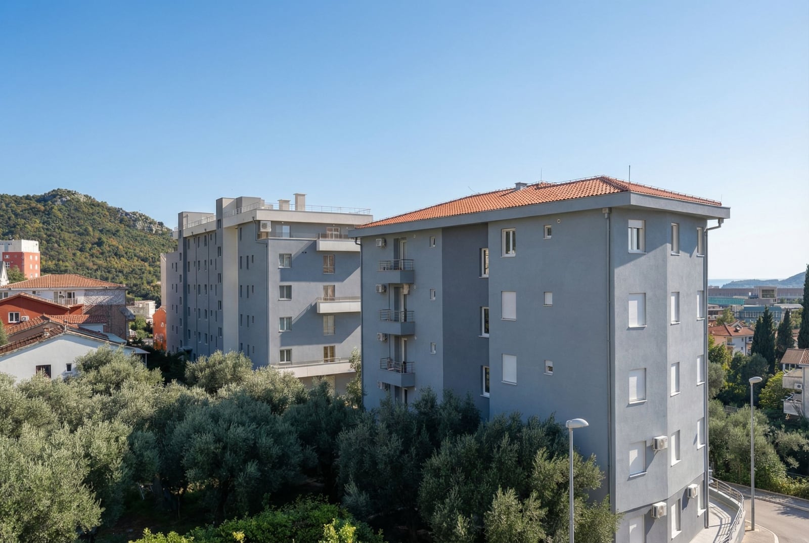 Modern residential buildings with tiled roofs surrounded by olive trees, Becici, Montenegro.