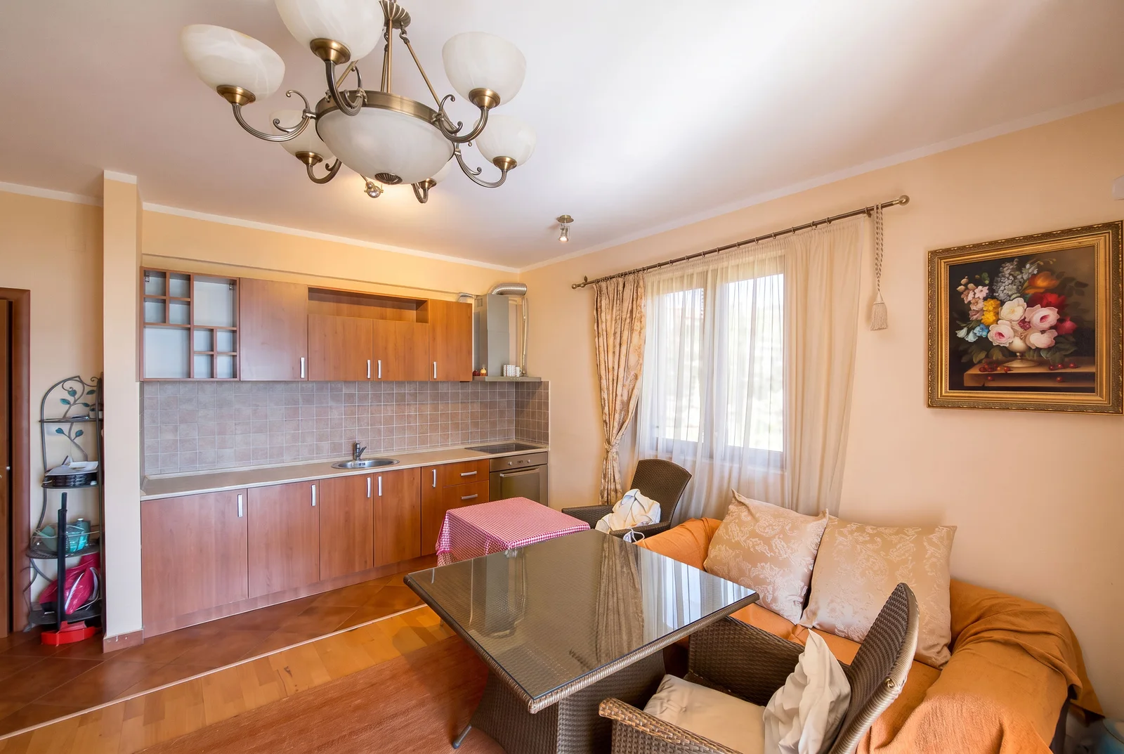 Kitchen with wooden cabinets, sink, and stove, combined with a dining table and sofa area.