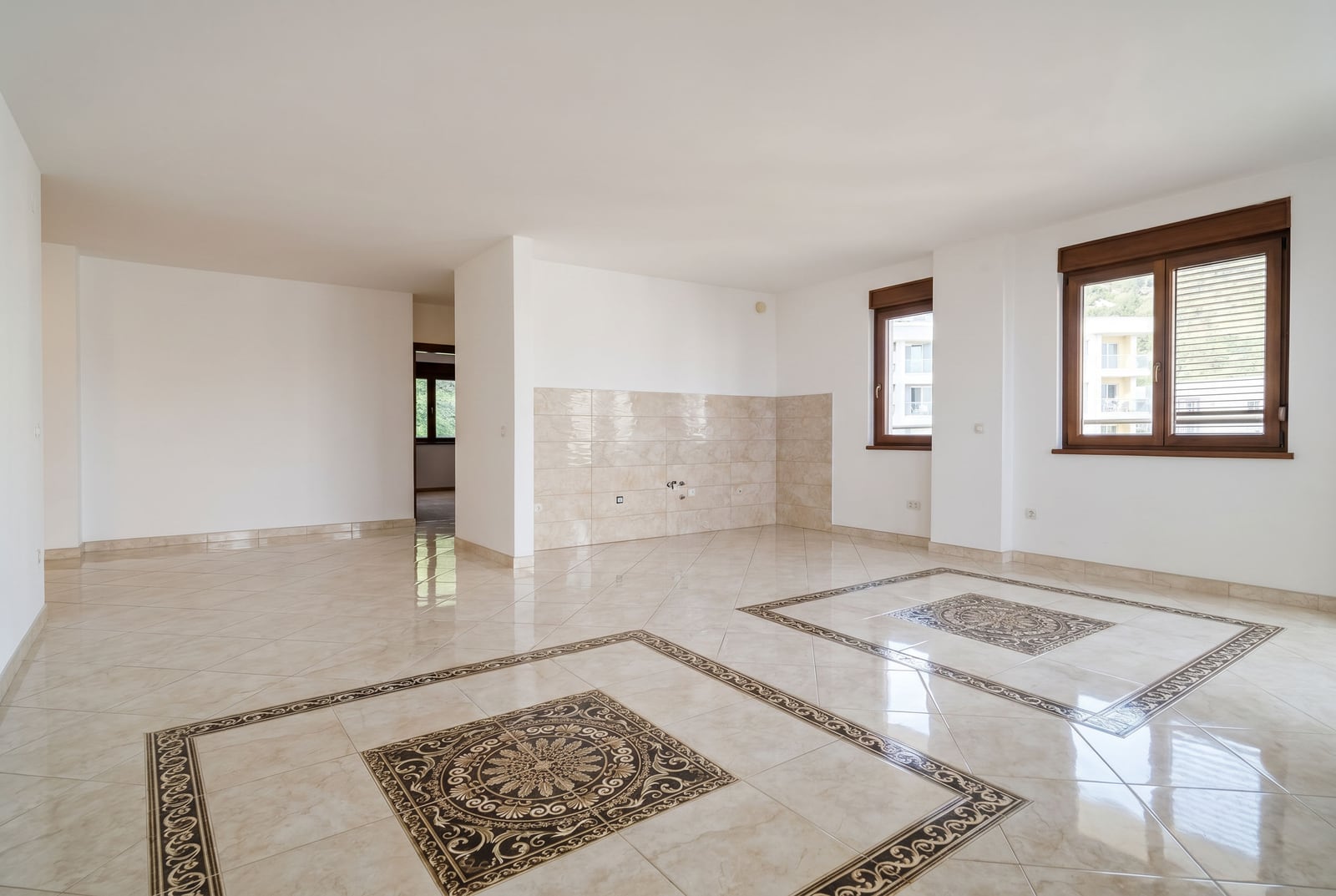 Bright living room with tiled floors and a kitchen area in an apartment for sale in Becici, Montenegro.