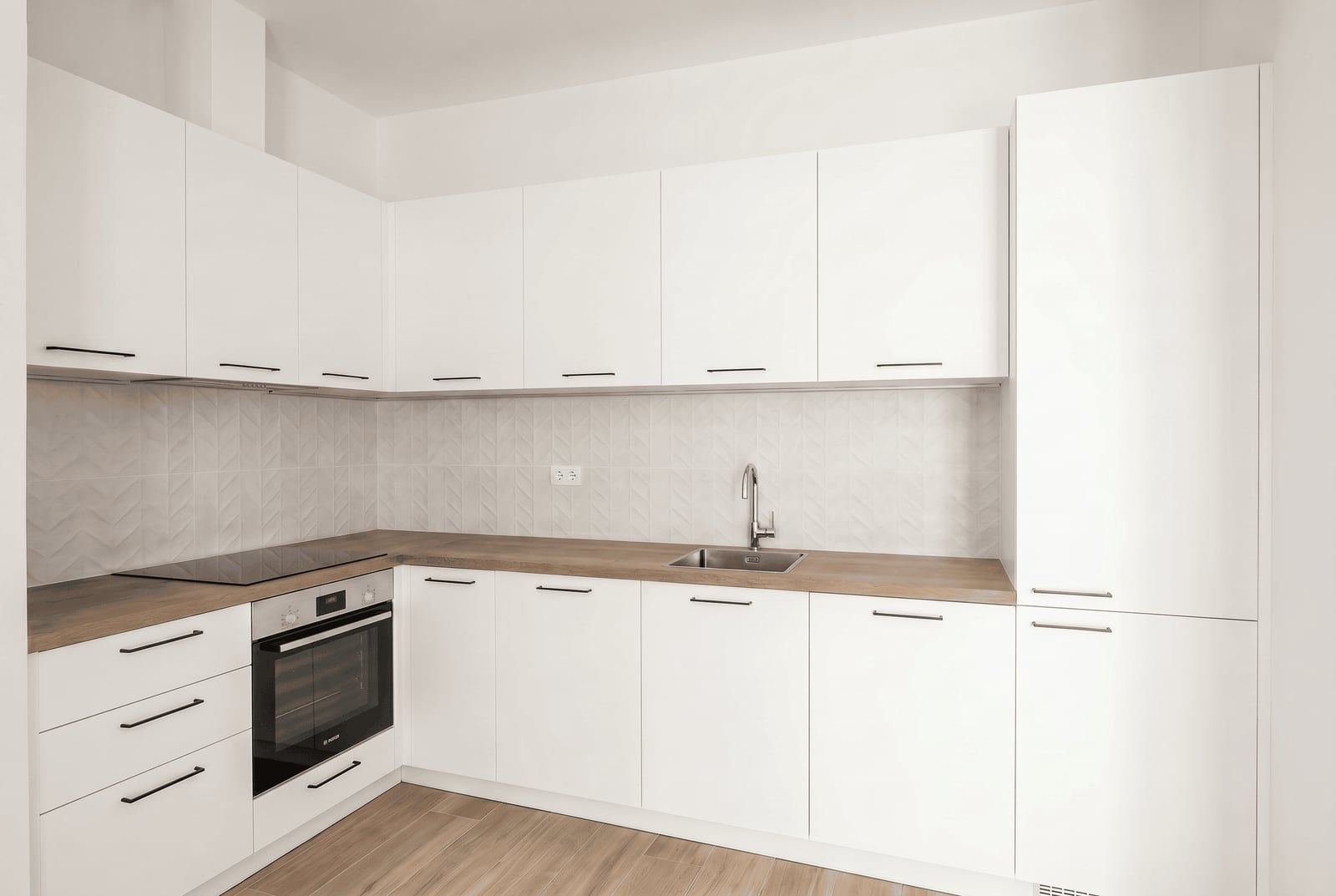 Modern white kitchen with a wooden countertop in an apartment at Luštica Bay, Montenegro: built-in appliances and tile.