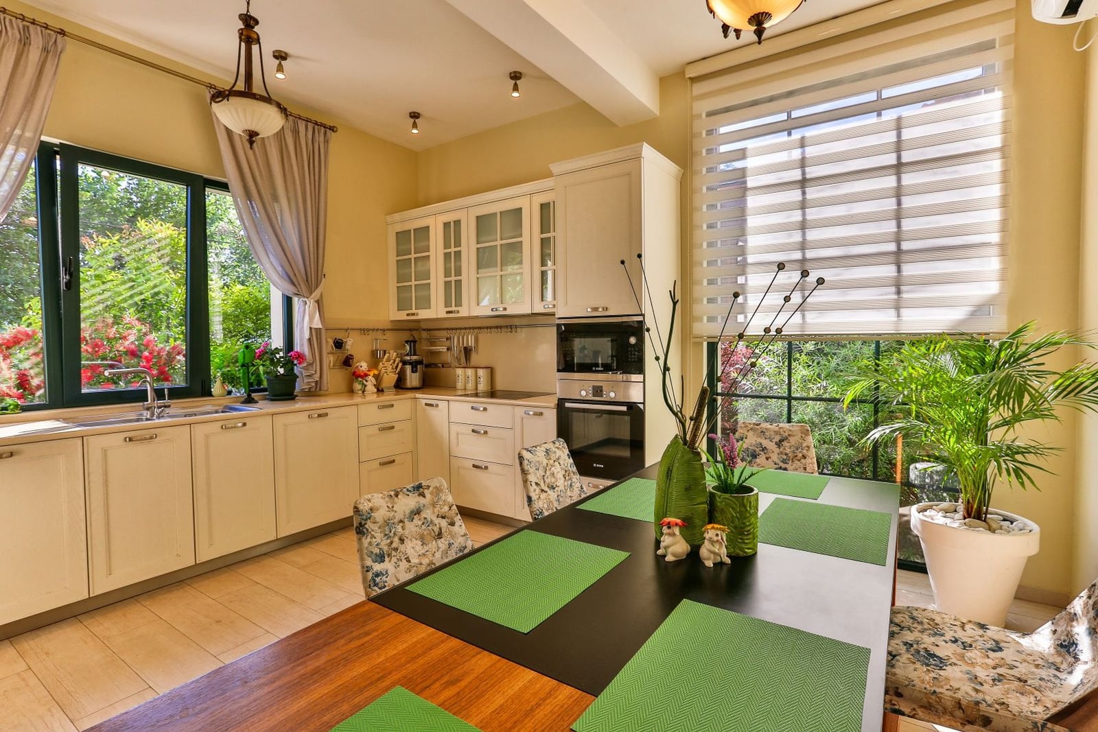 Bright kitchen-dining room in a villa in Tivat, Montenegro: classic kitchen set, dining table, and a view of the green garden.