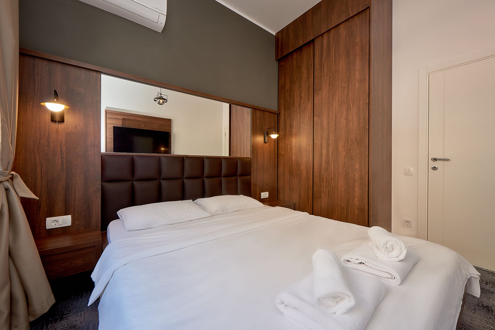 Modern bedroom with a double bed and a wooden wardrobe in an apartment, Becici, Montenegro.