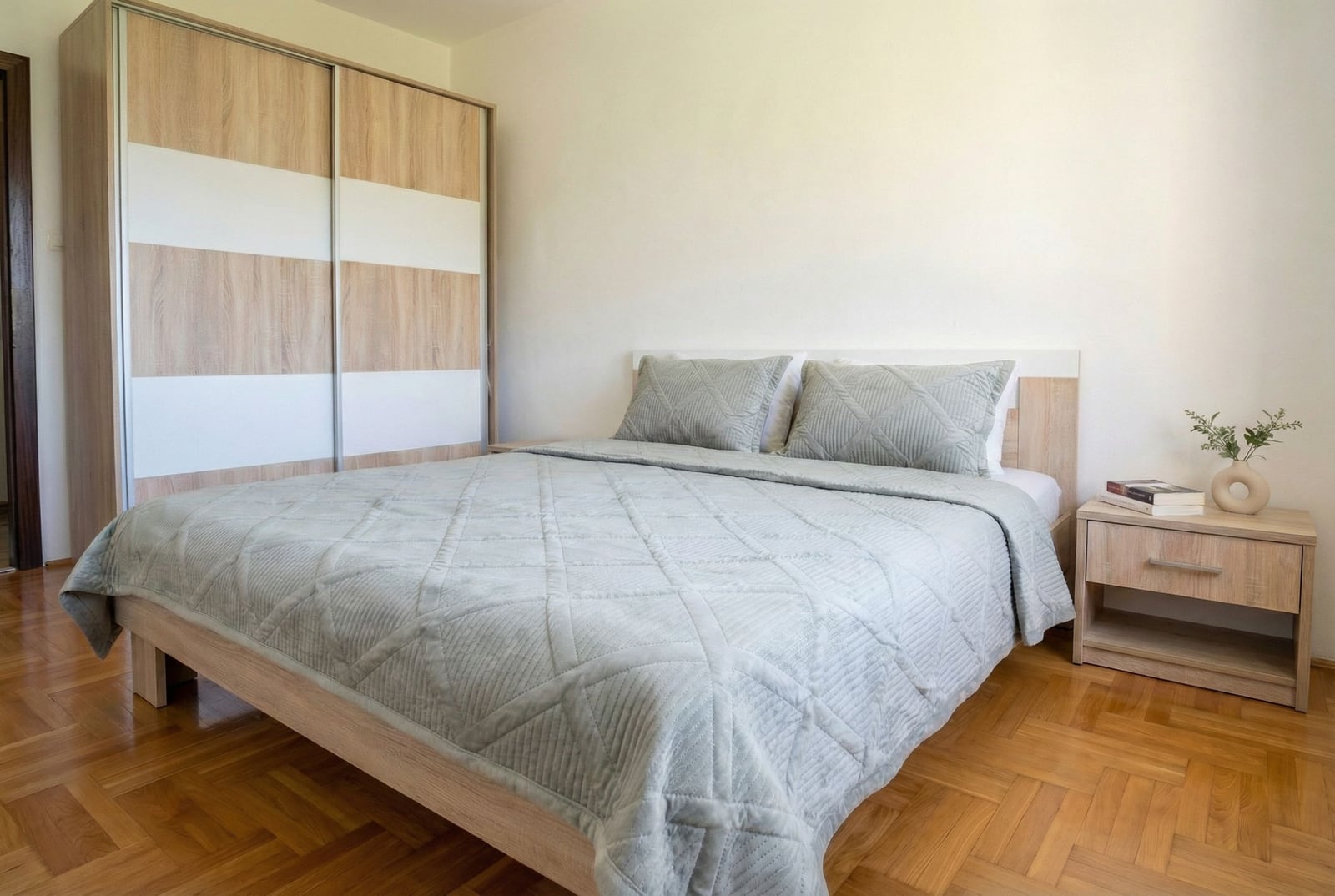 Bright bedroom in an apartment in Budva, Montenegro: double bed, built-in wardrobe, and parquet flooring in a modern style.