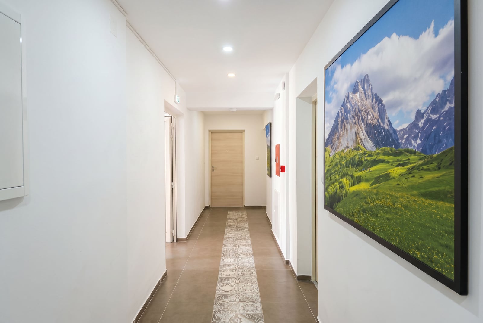 Bright hallway in an apartment in Bečići, Montenegro, with tiled flooring, interior doors, and a mountain painting.
