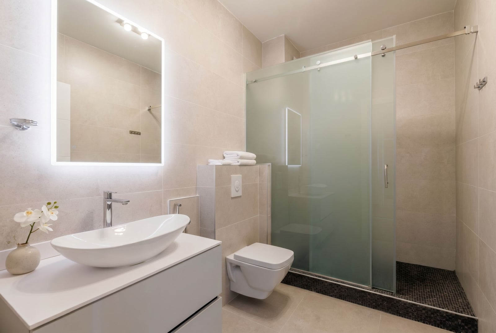 Modern bathroom in a penthouse in Becici, Montenegro: walk-in shower, wall-mounted toilet, and stylish sink.