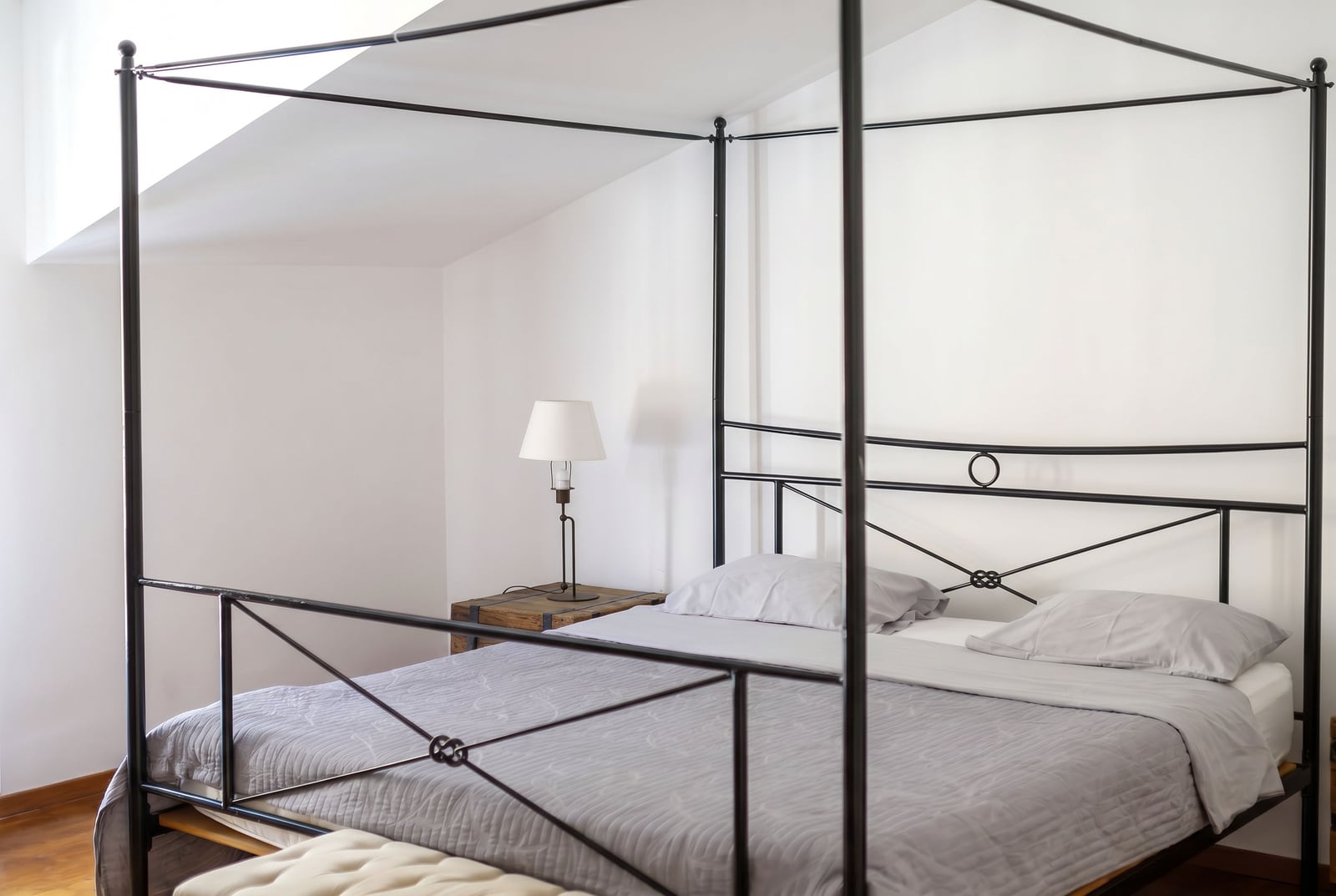 Bedroom in a penthouse in Risan, Montenegro: a double bed with a black wrought iron frame and a light interior.