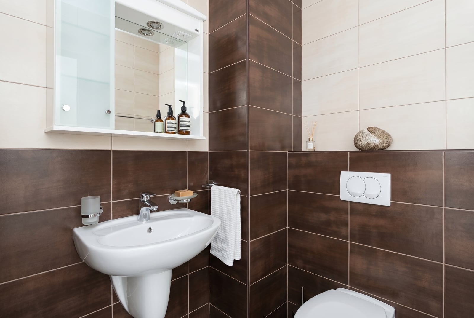 Modern bathroom with brown tiles and white sanitary ware in an apartment in Budva, Montenegro.