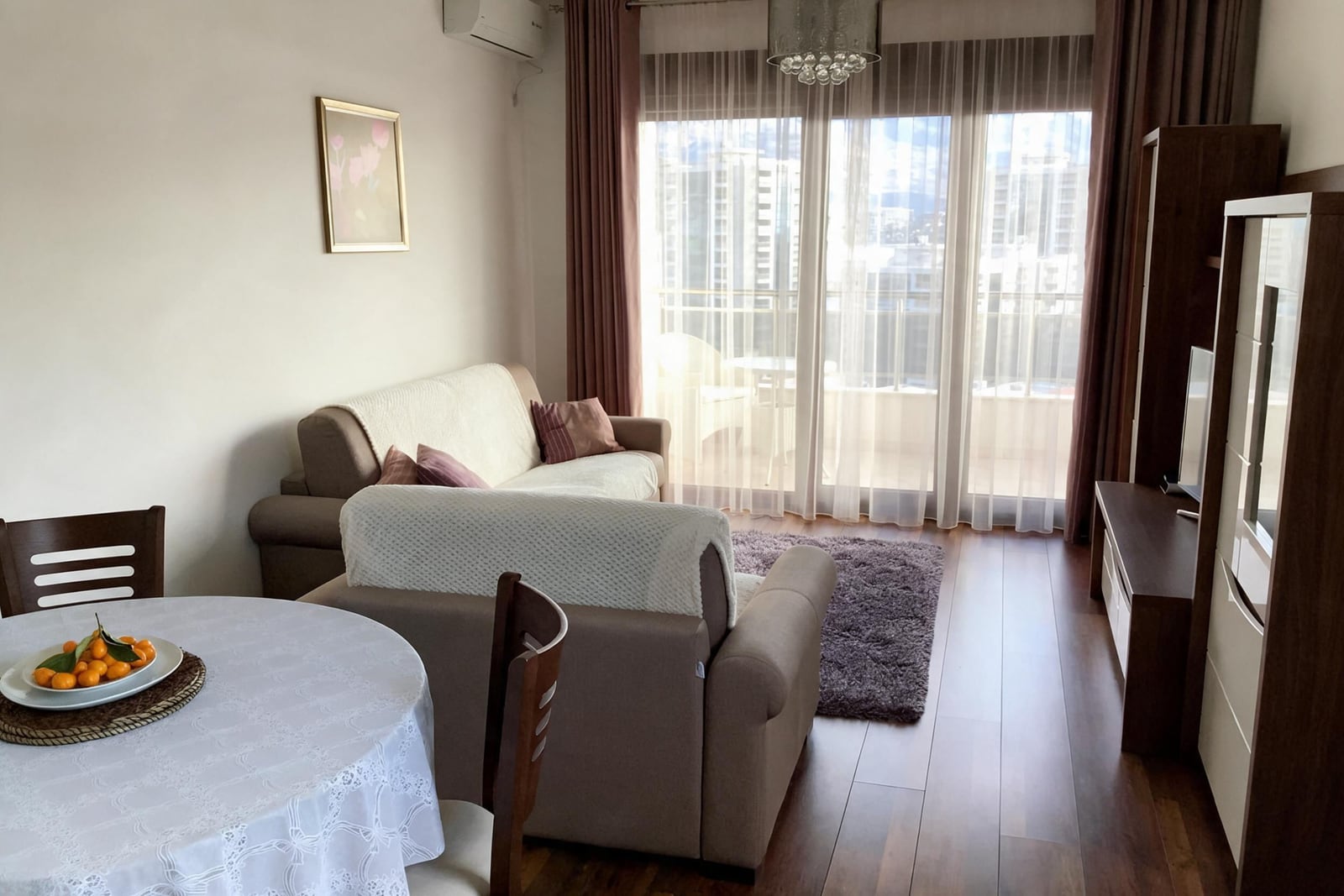 Living room featuring a sofa, dining table with fruit, TV unit, and large window with balcony access.