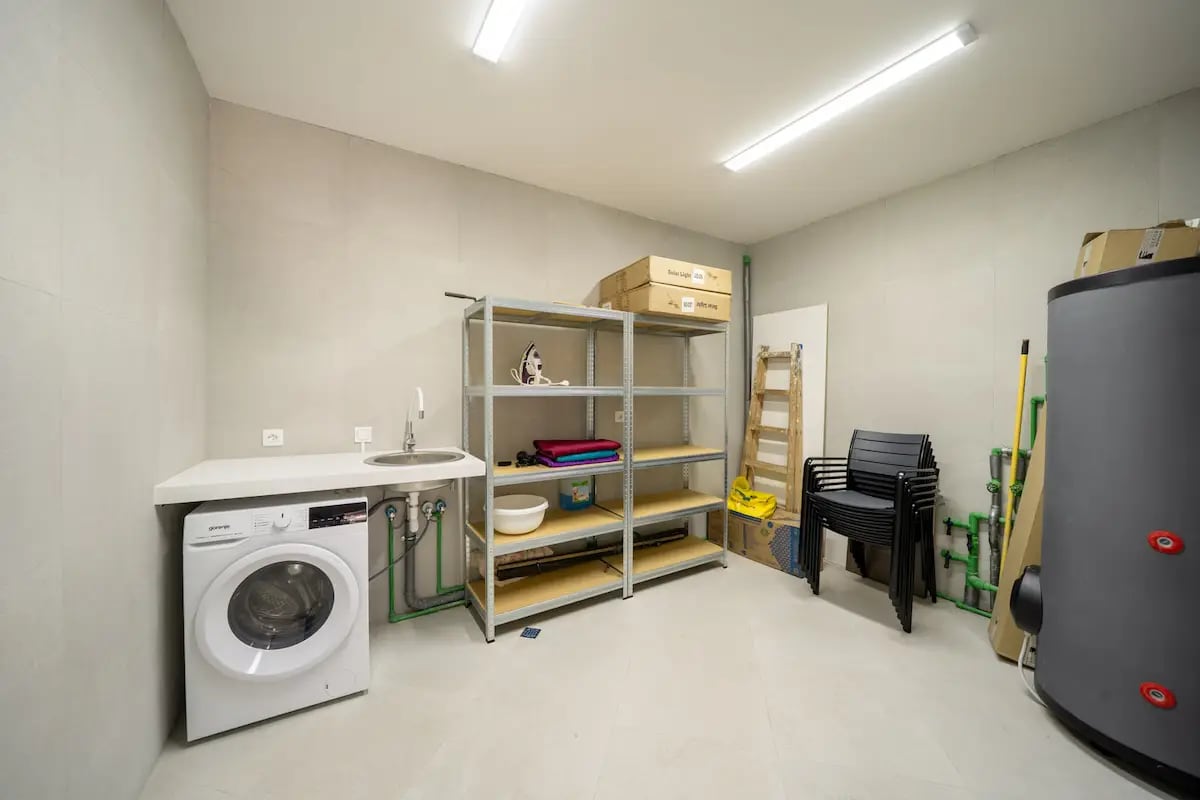 Utility room with a laundry area, shelving units, and a water heater in a villa in Reževići, Montenegro.