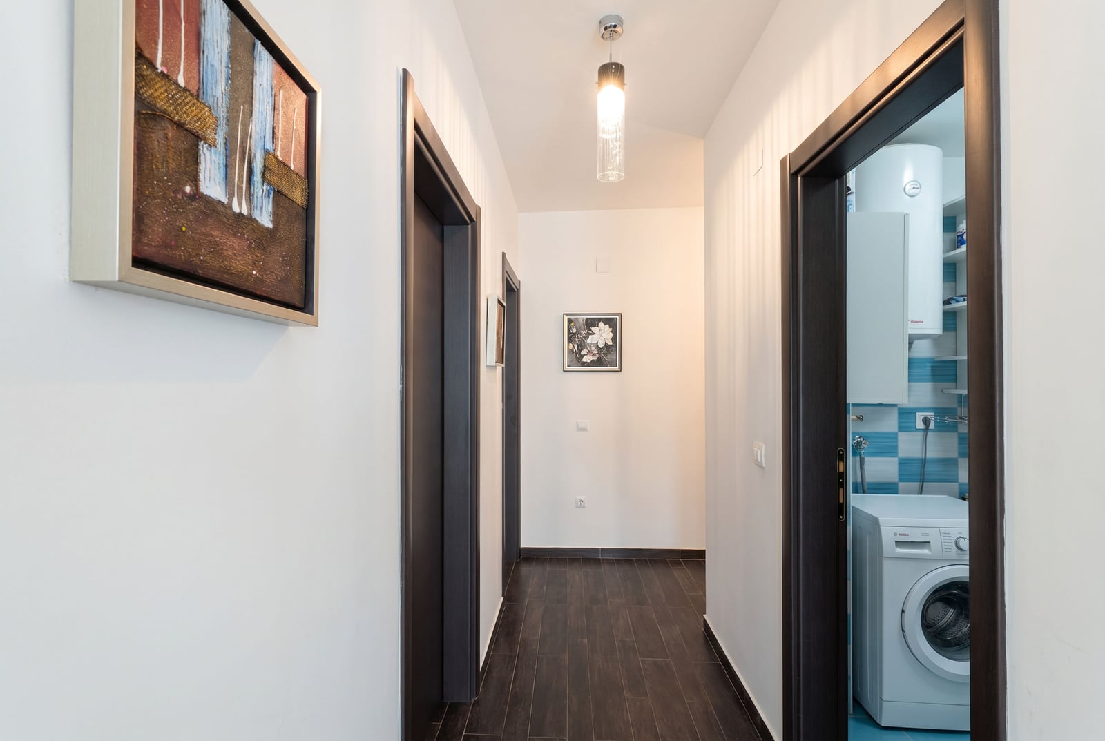 Bright hallway in an apartment, Kumbor, Montenegro: dark flooring, interior doors, and a view of the bathroom with a washing machine.