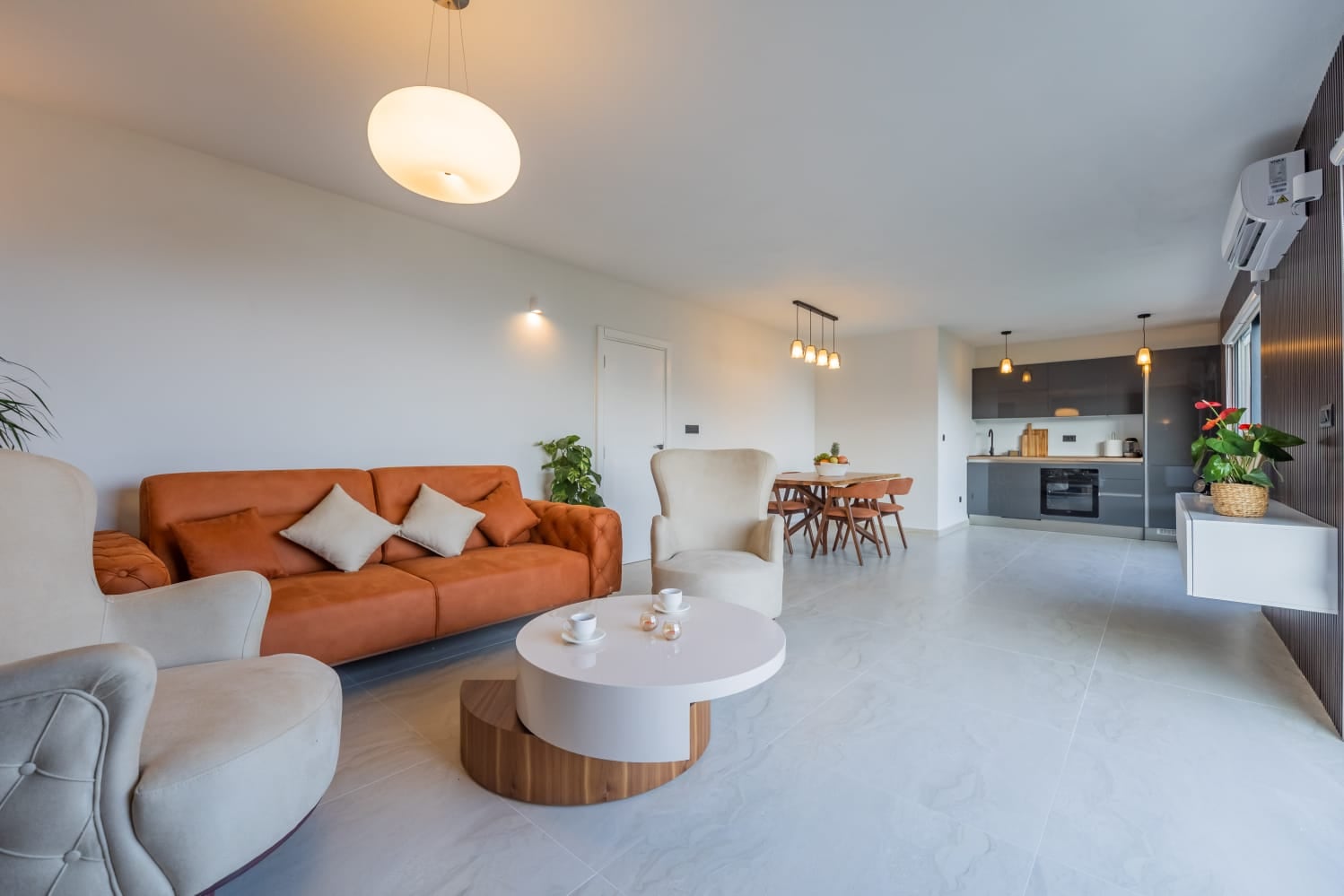 Modern living room with an orange sofa and kitchen in a villa in Budva, Montenegro: stylish interior, light finishes.