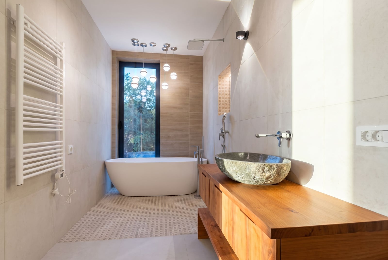 Modern bathroom in a villa in Kavac, Montenegro: freestanding bathtub, stone sink, and forest view.