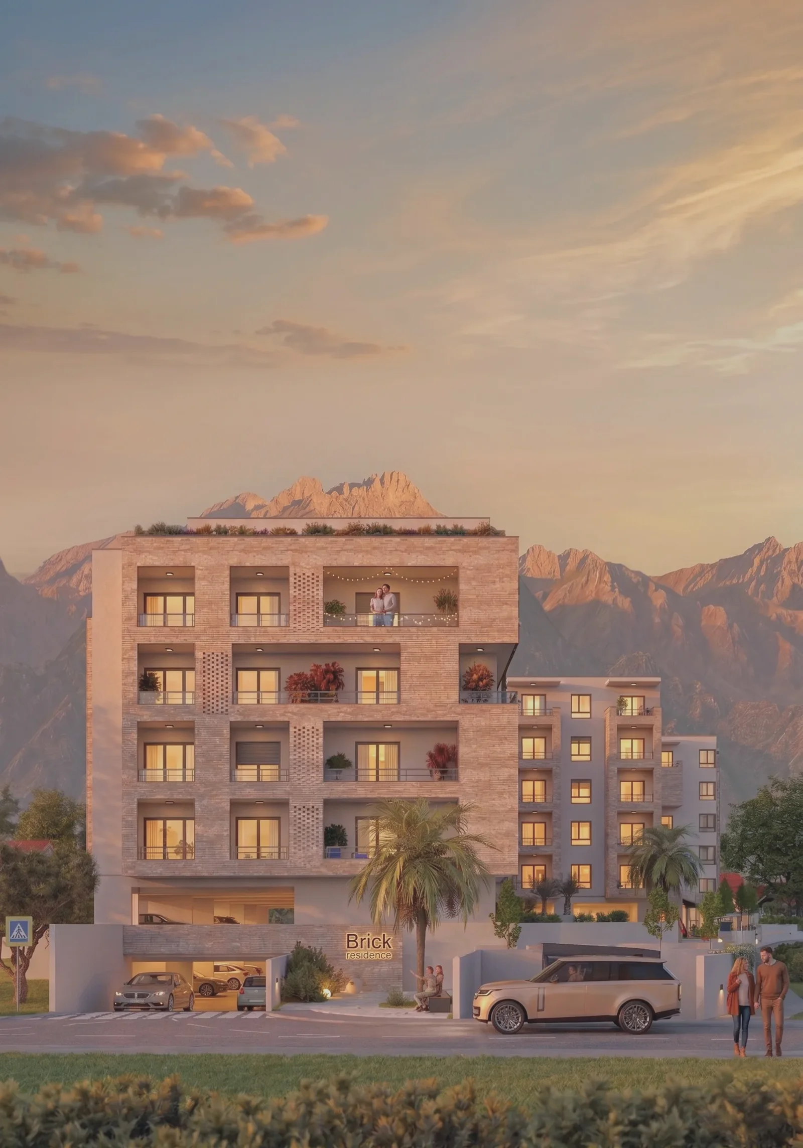 Exterior view of a multi-story residential building with balconies set against a mountain range at dusk.