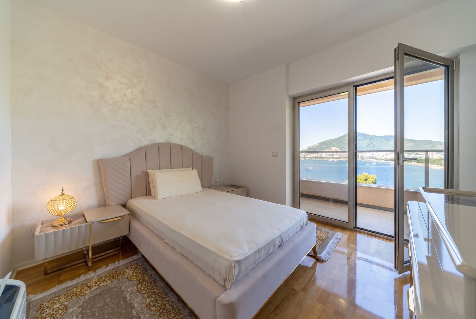 Bedroom with a double bed and panoramic sea view in an apartment in Bečići, Montenegro