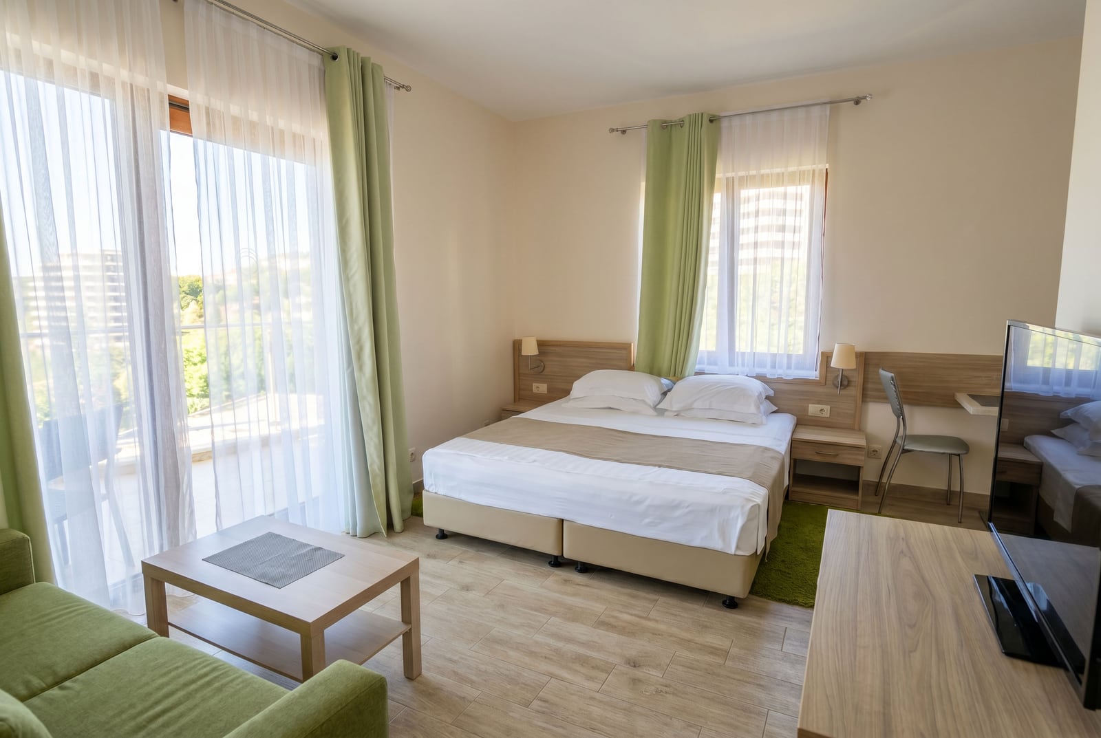 Bright bedroom with a double bed, balcony access, and furniture in an apartment in Becici, Montenegro.