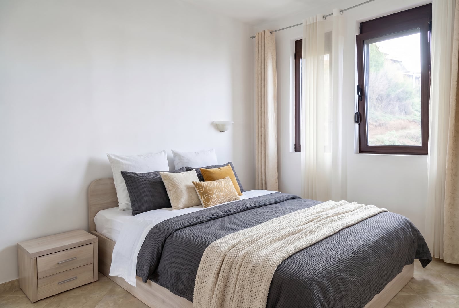 Bright bedroom with a double bed in an apartment, Rafailovici, Montenegro: modern furniture and a view from the window.
