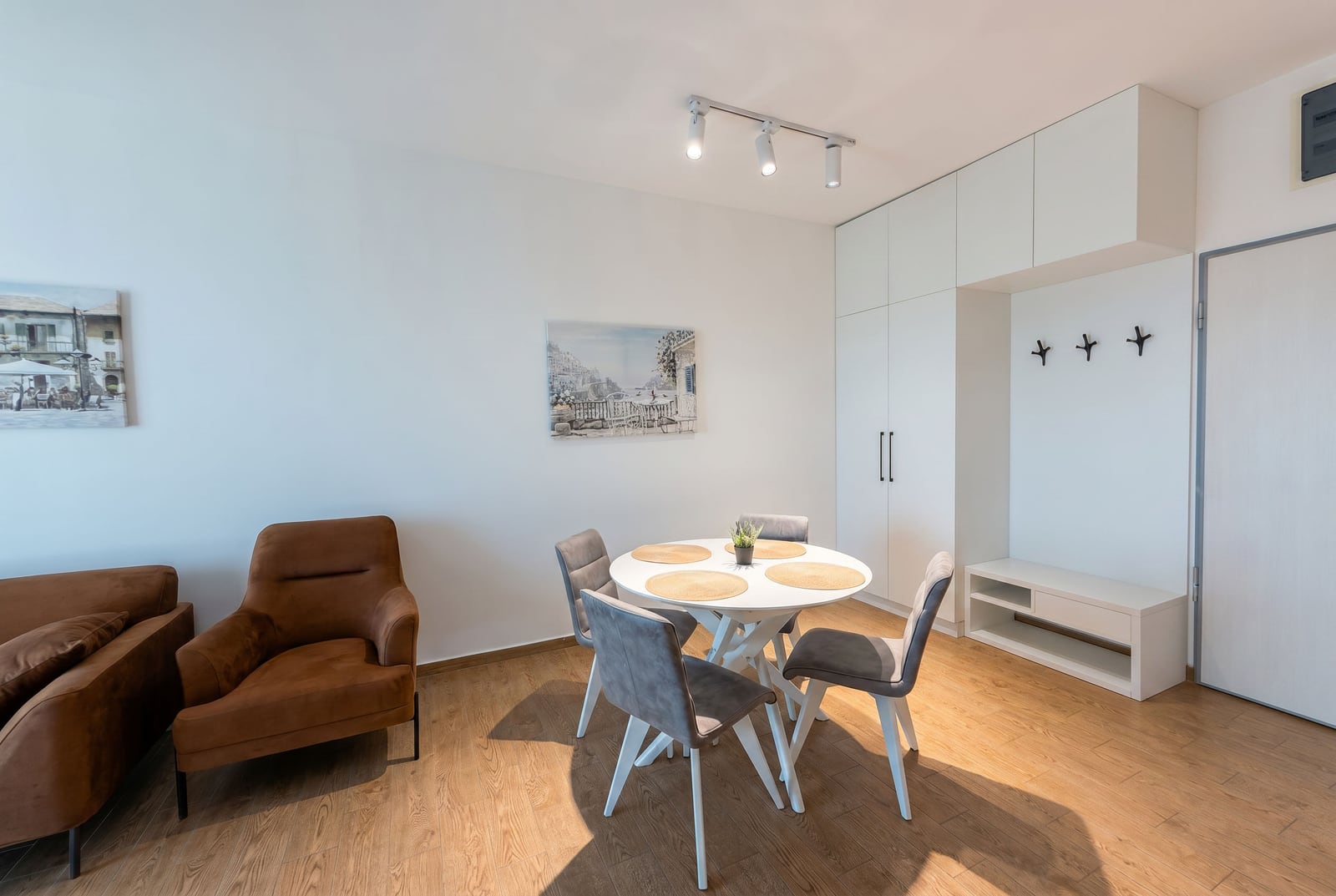 Modern living room with a dining area in an apartment, Becici, Montenegro: brown armchair, round table, and wardrobe.