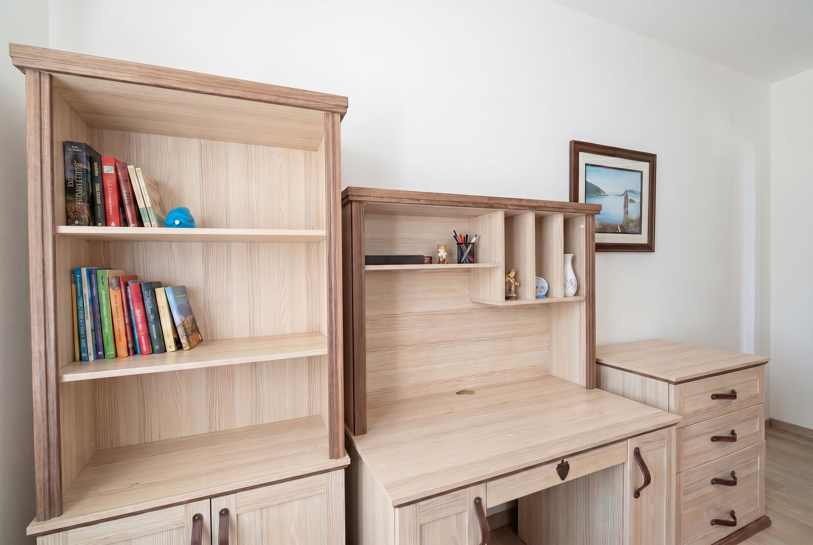 Work area in the bedroom of an apartment in Kumbor, Montenegro: light wooden shelving unit, writing desk, and chest of drawers.