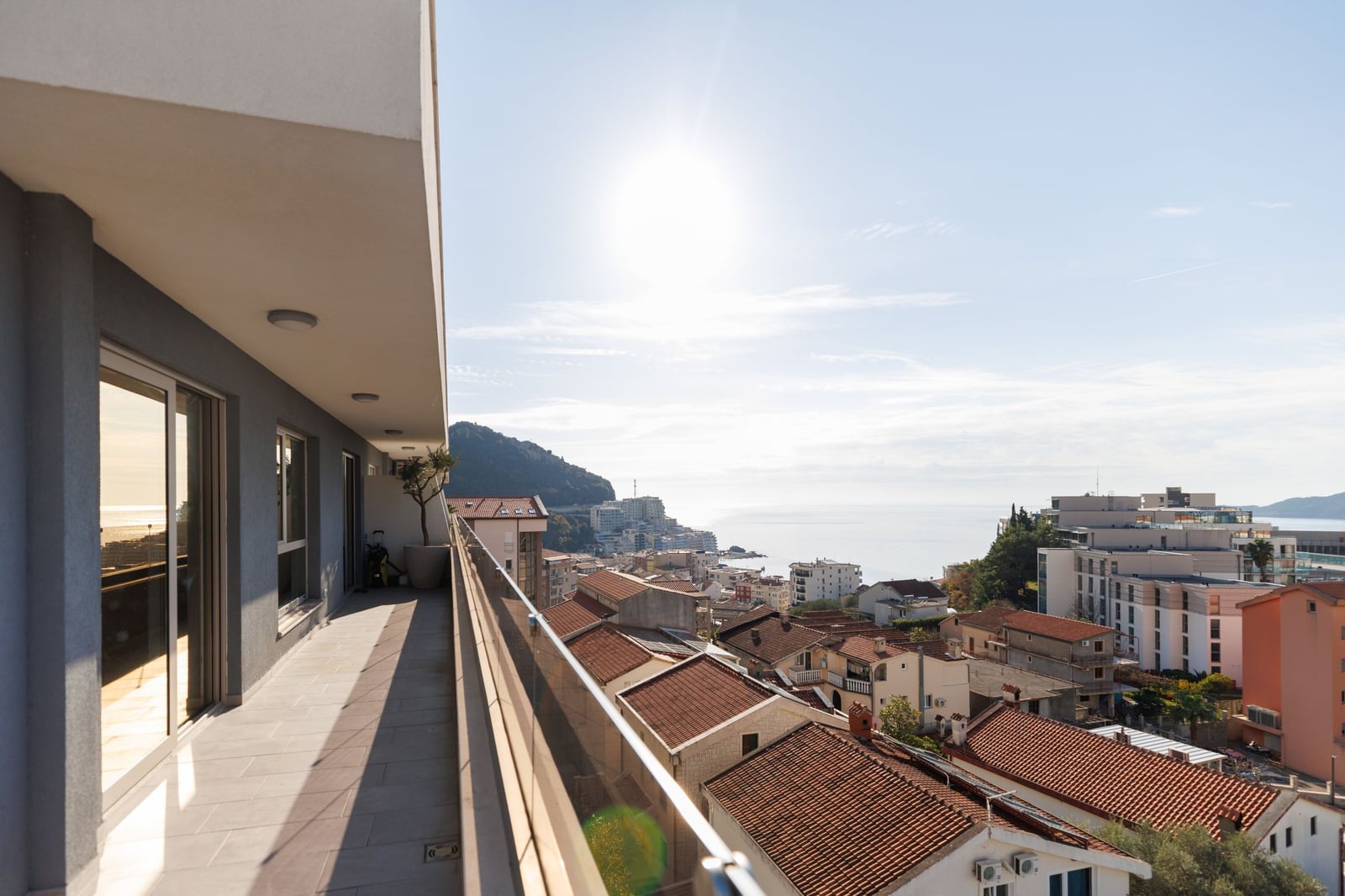 Spacious penthouse balcony in Becici, Montenegro, with panoramic views of the sea, mountains, and the town's tiled roofs.