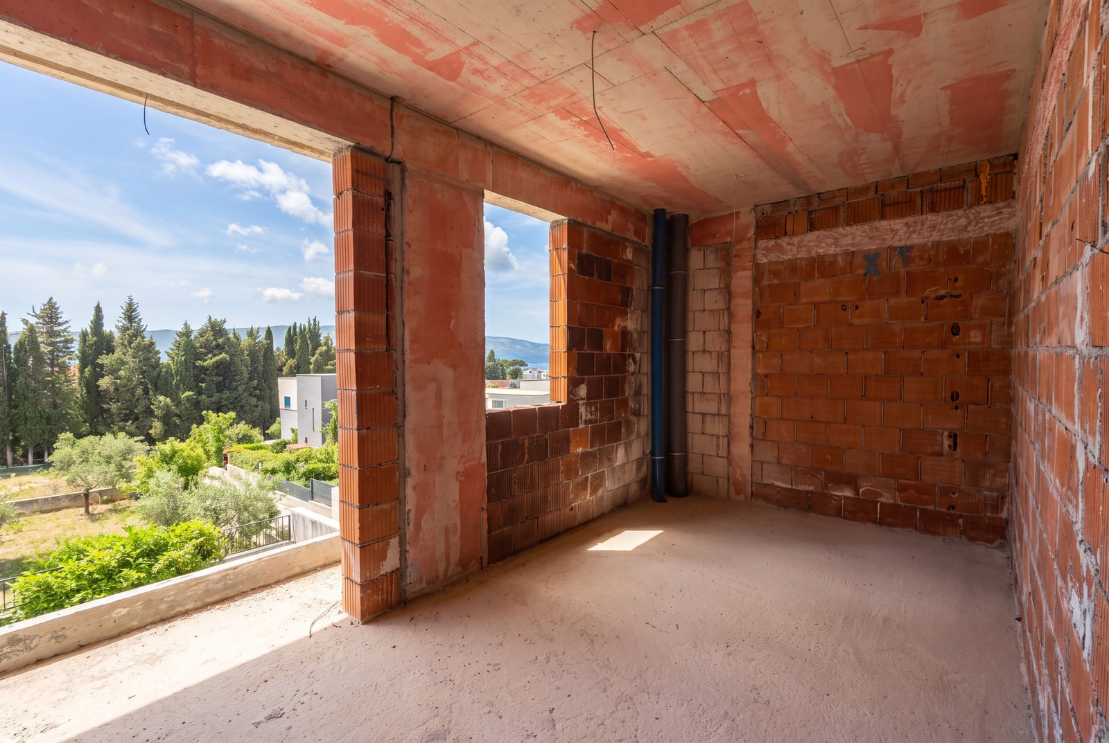 Apartment in a new development in Tivat, Montenegro: raw brick walls, panoramic windows, and a view of greenery.