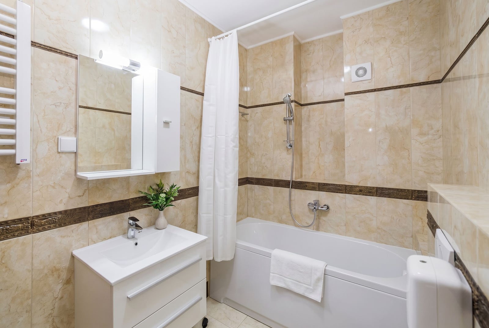 Bathroom with white sanitary ware and beige tiles in an apartment in Bečići, Montenegro. Modern bathroom interior.