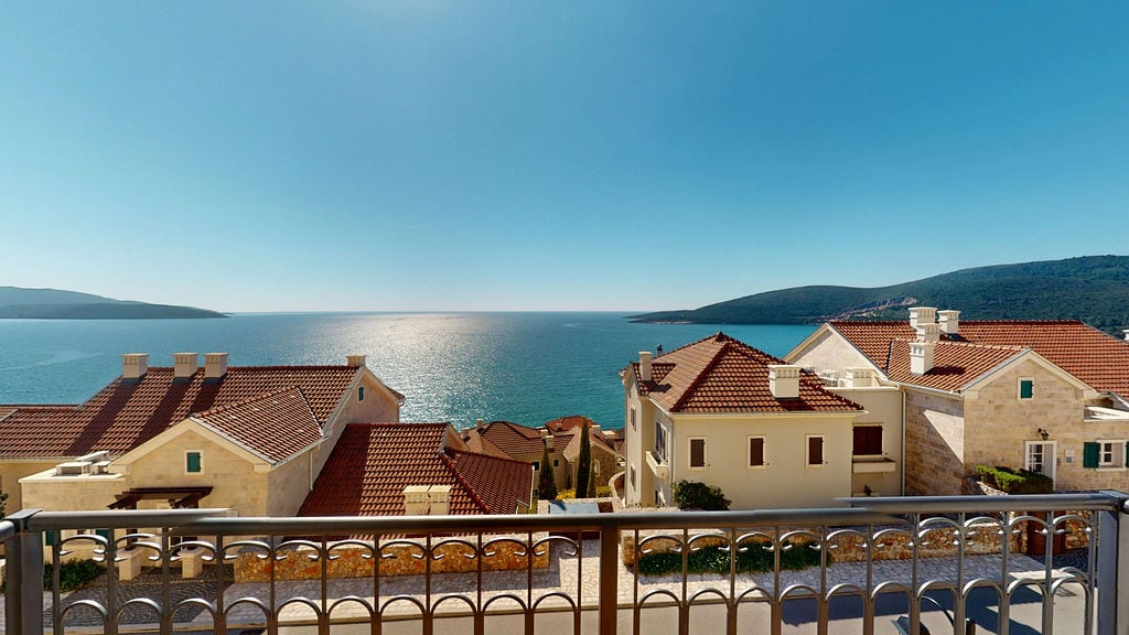 Sea view from the balcony overlooking Mediterranean villas in Luštica, Montenegro. Coastal panorama from the apartment terrace.