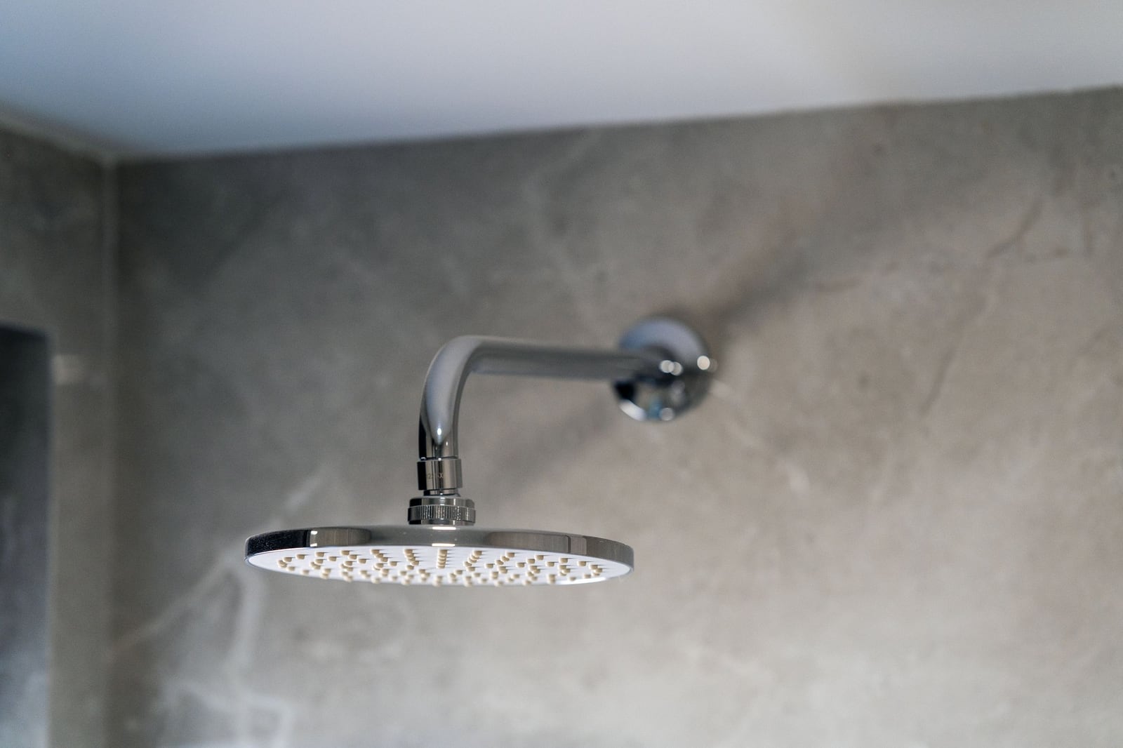 Chrome showerhead in a modern apartment bathroom in Budva, Montenegro, with gray stone finishes.