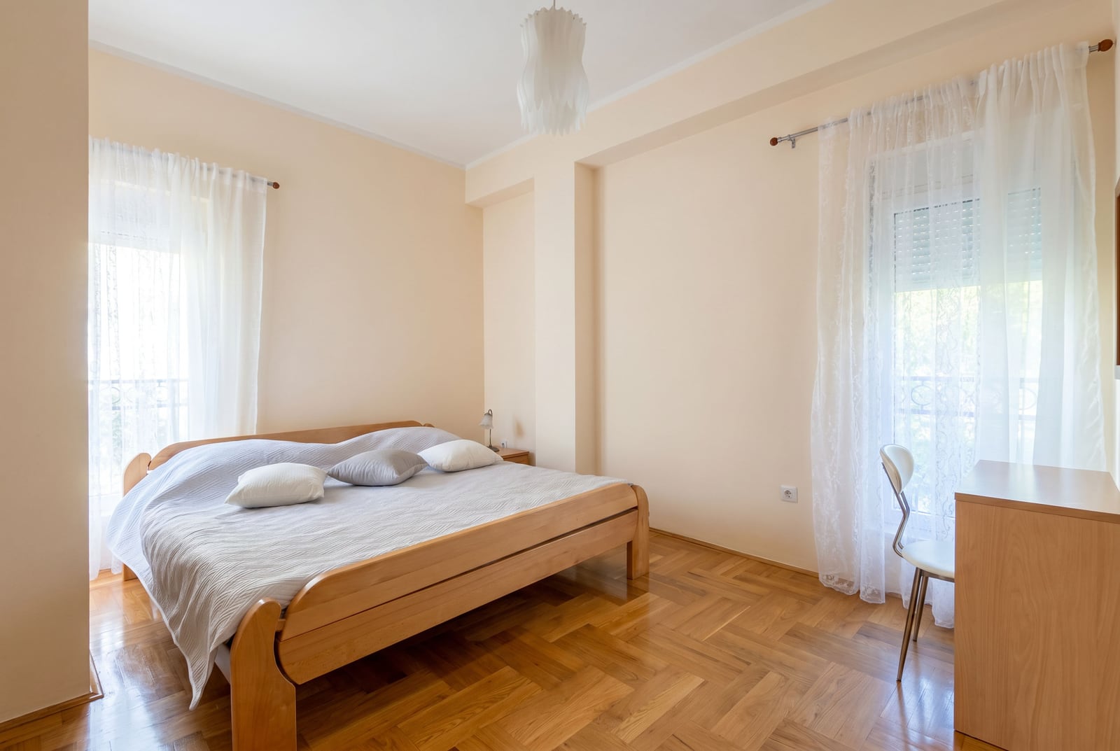 Bright bedroom with a double bed and parquet flooring in an apartment for sale in Budva, Montenegro.